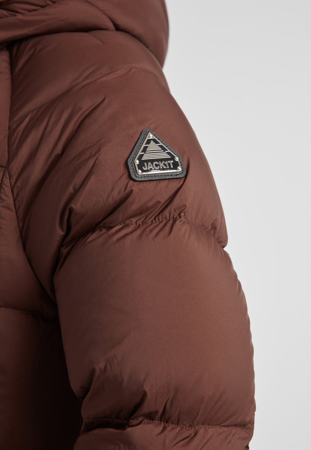 Close-up of the JACK1T logo on the Ladies Cloud Crop Down Puffer Jacket in Mid Brown.