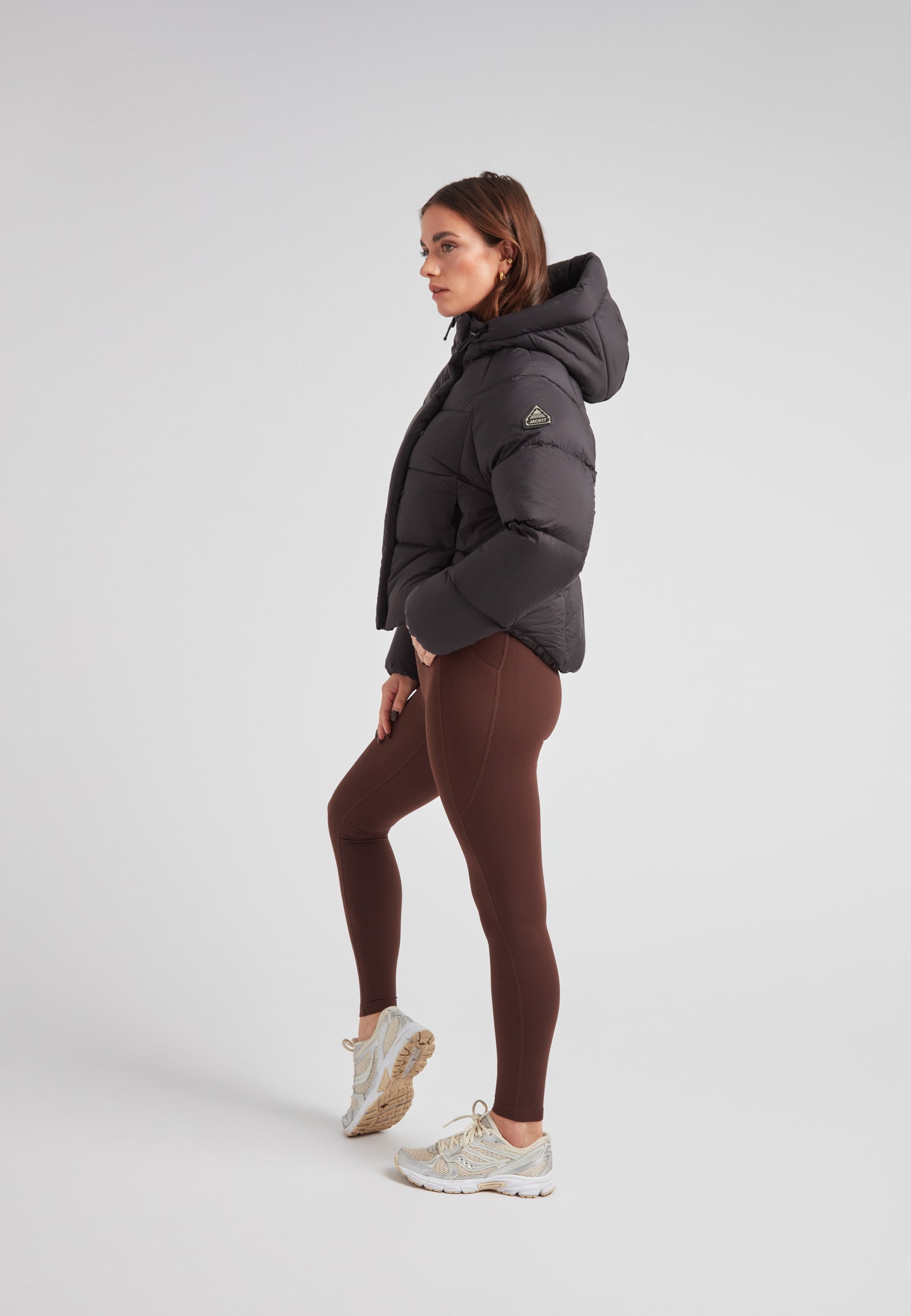 Woman wearing a cloud crop down puffer jacket black with leggings and sneakers, showcasing stylish cold-weather fashion.