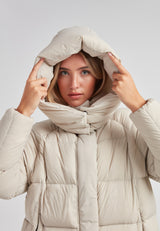Model wearing the Cloud Prime Longline Down Puffer Jacket Stone, adjusting the hood for warmth.