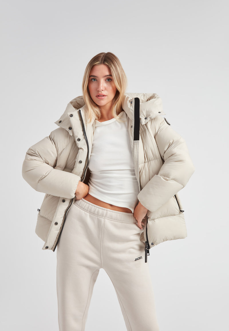 Cloud Prime Longline Down Puffer Jacket Stone worn by a model, showcasing its stylish mid-shine water-repellent design.