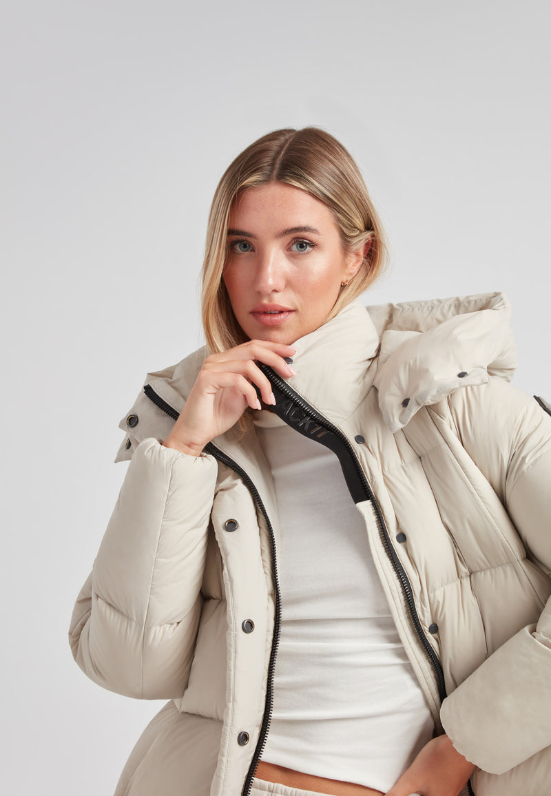 Model wearing Cloud Prime Longline Down Puffer Jacket Stone with adjustable hood and zip detail.