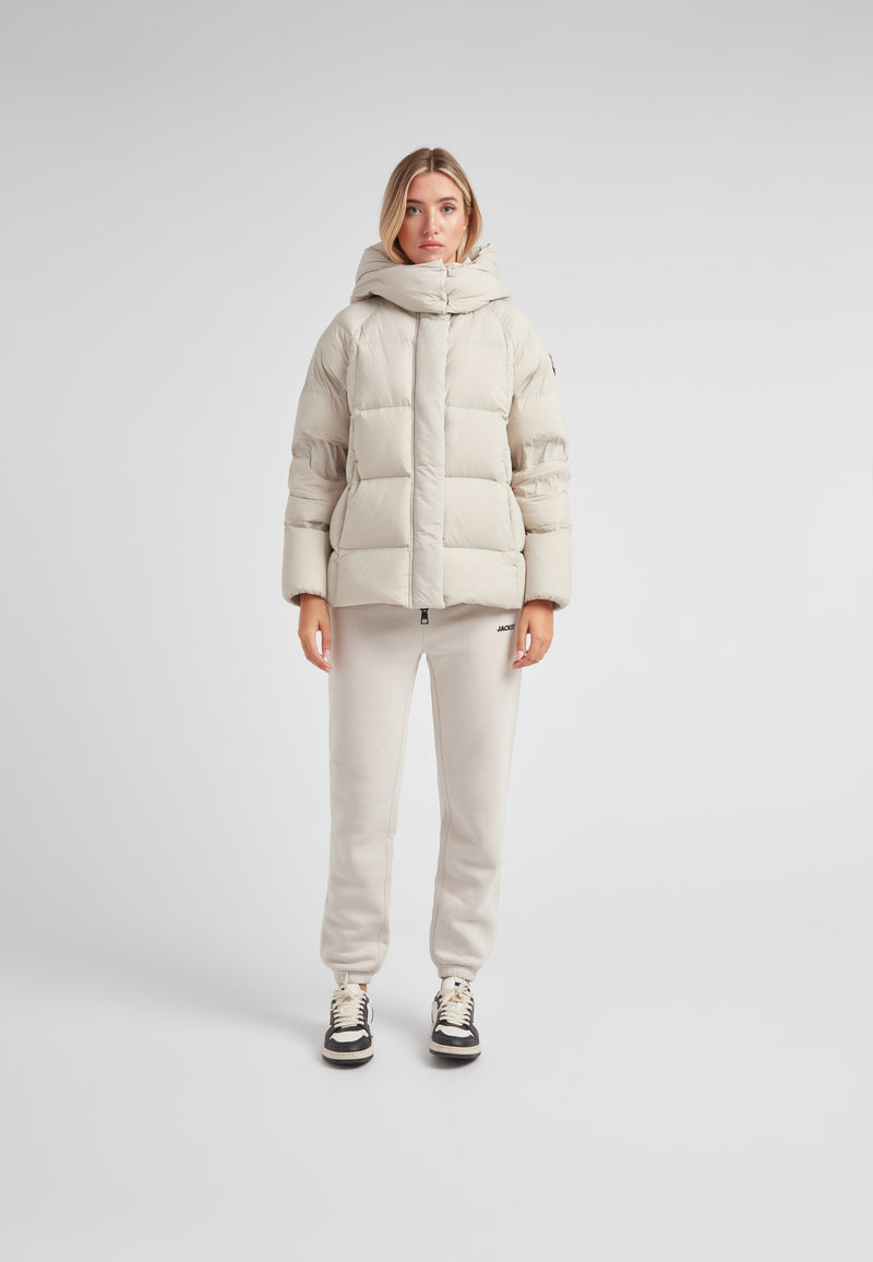 Woman wearing Cloud Prime Longline Down Puffer Jacket Stone, showcasing its stylish and warm design.