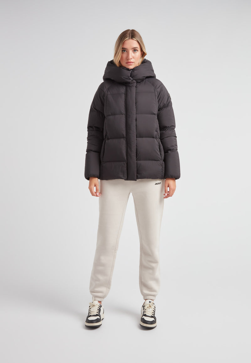 Woman in Cloud Prime Longline Down Puffer Jacket with adjustable hood, styled with cream sweatpants.
