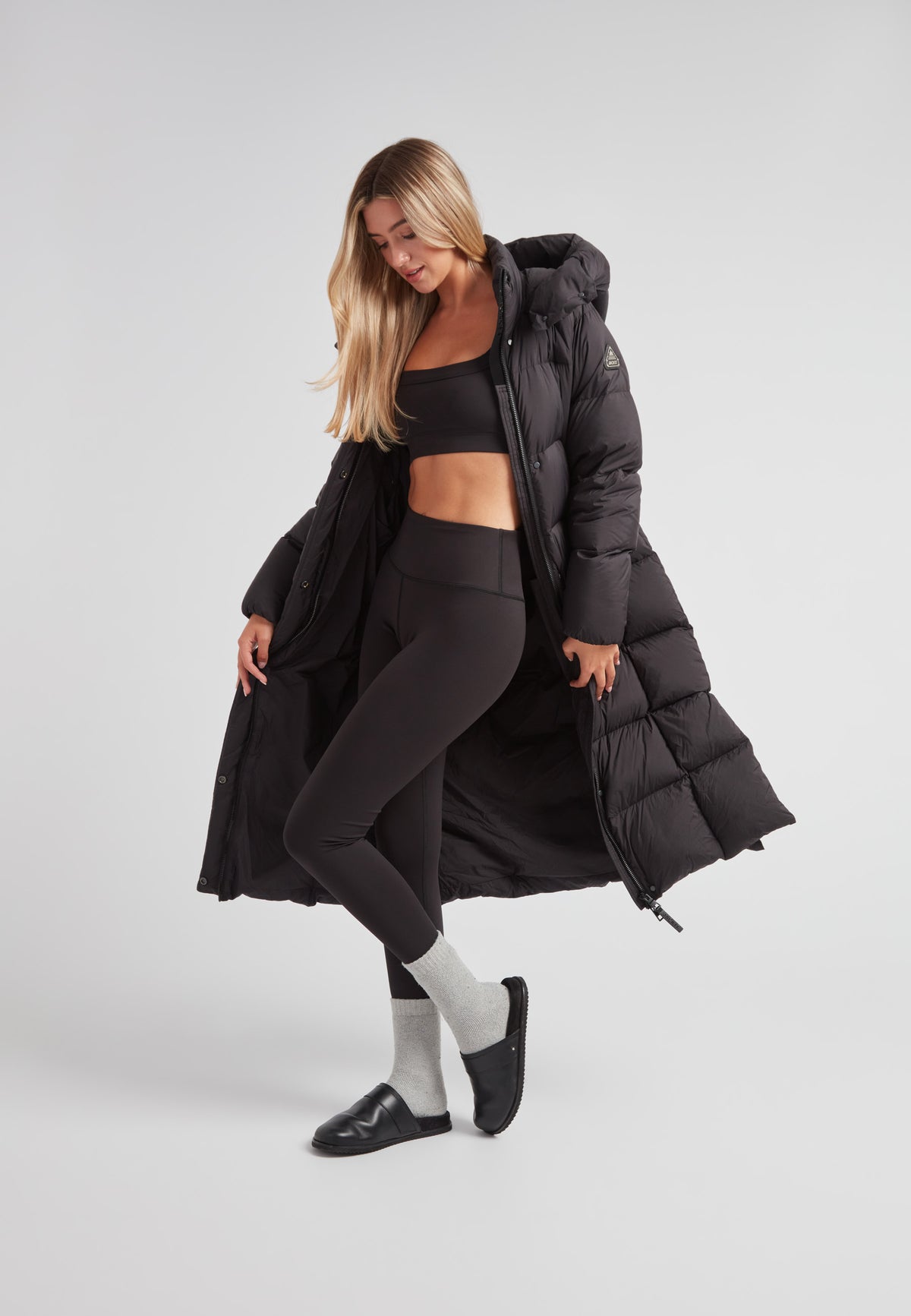 Model wearing a Long puffer jacket in black with sporty outfit and stylish knee-length design.