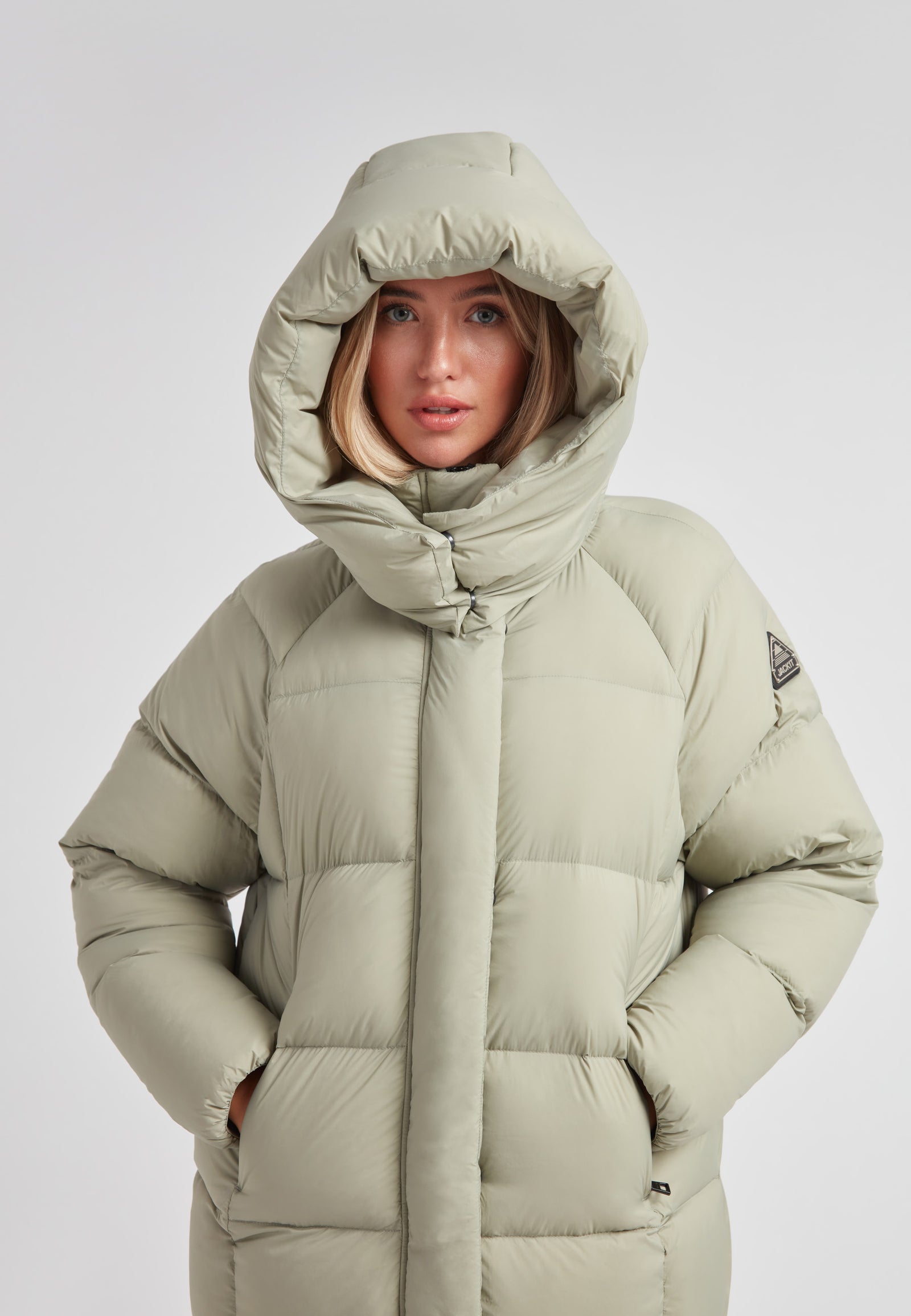 Woman wearing a Cloud Ultra Long Down Puffer Coat with a hood, showcasing its warmth and stylish design.