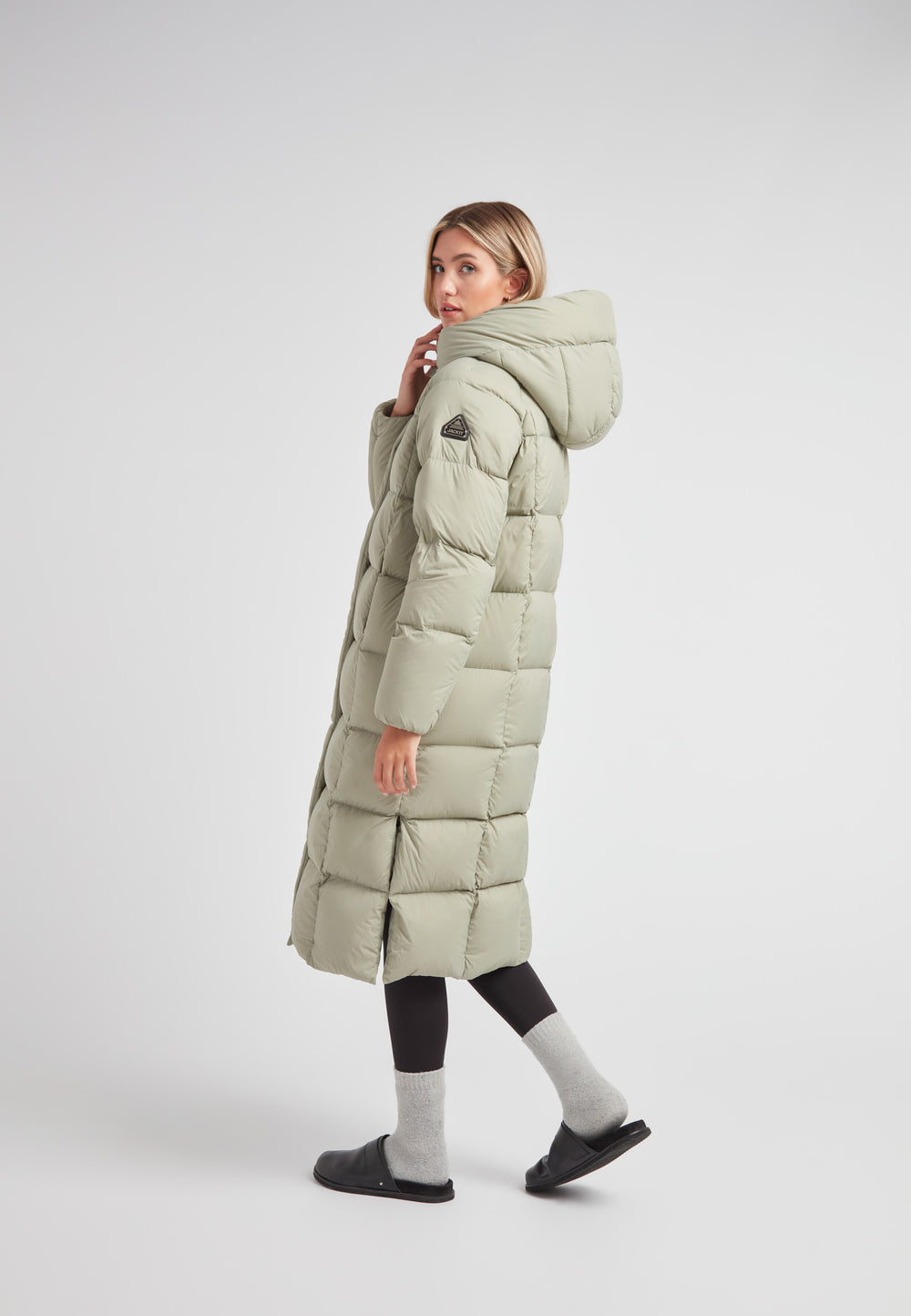 Woman wearing a green Cloud Ultra Long Down Puffer Coat, showcasing its ankle-length and adjustable hood design.