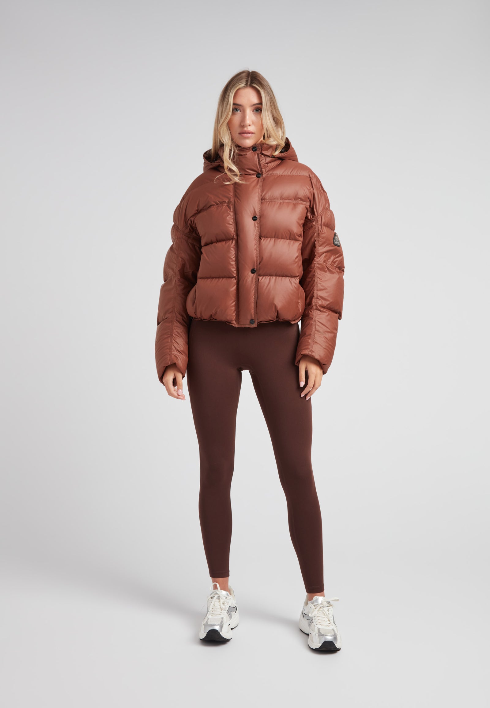 Cropped puffer in mocha brown with adjustable coverage worn by a model with leggings.