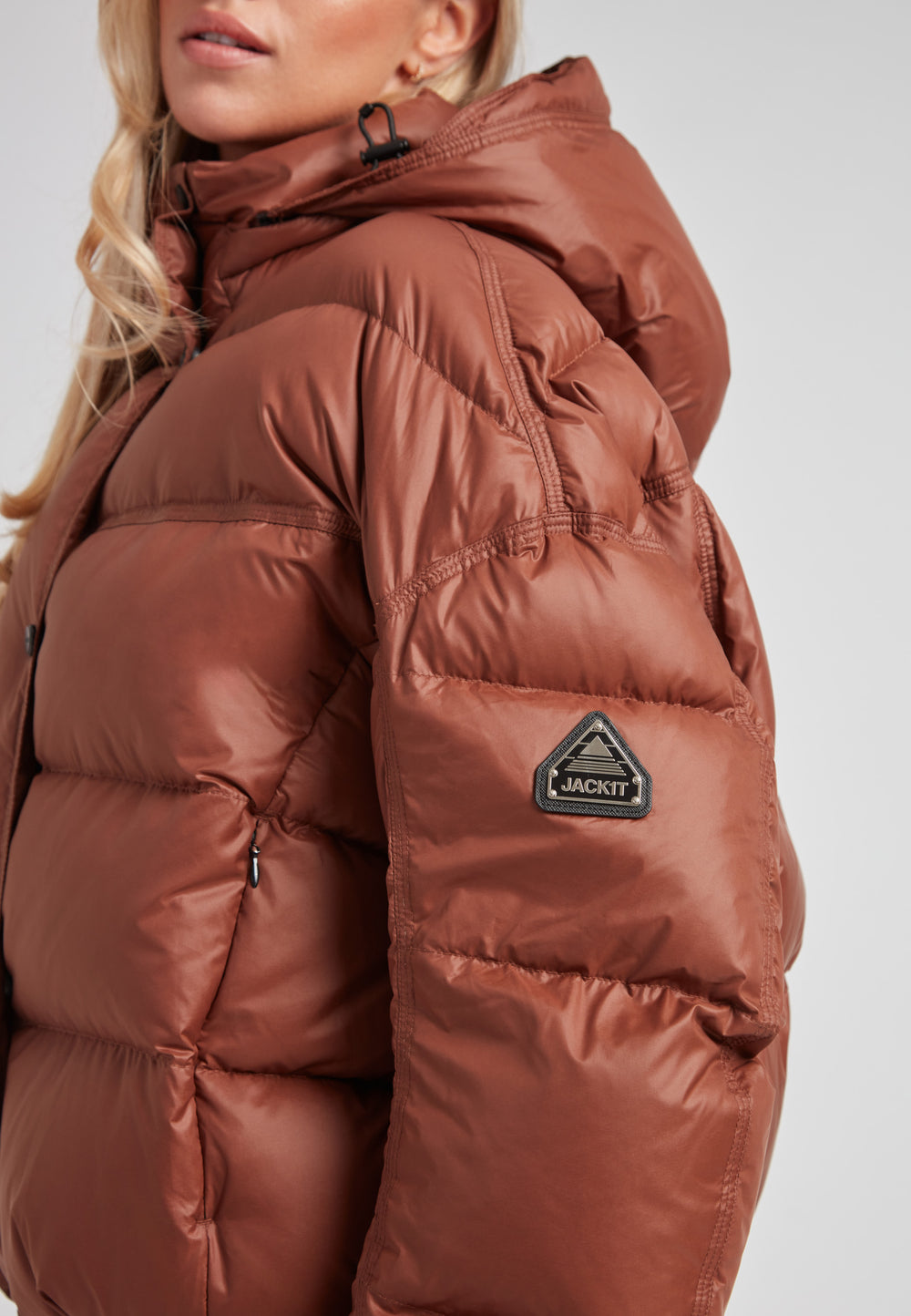 Cropped puffer in mocha brown with adjustable coverage, featuring JACK1T logo and oversized design.