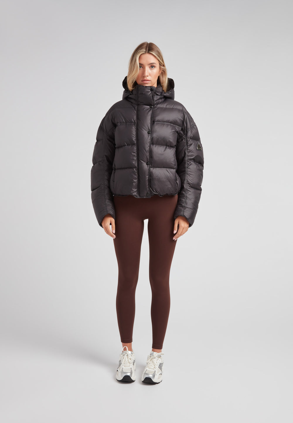 Cropped puffer in black with adjustable coverage, featuring oversized design and removable hood.