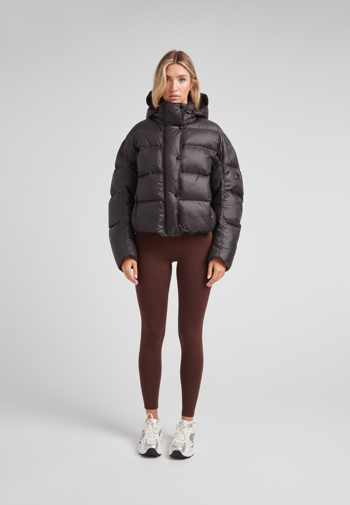 Cropped puffer in black with adjustable coverage, featuring oversized design and removable hood.