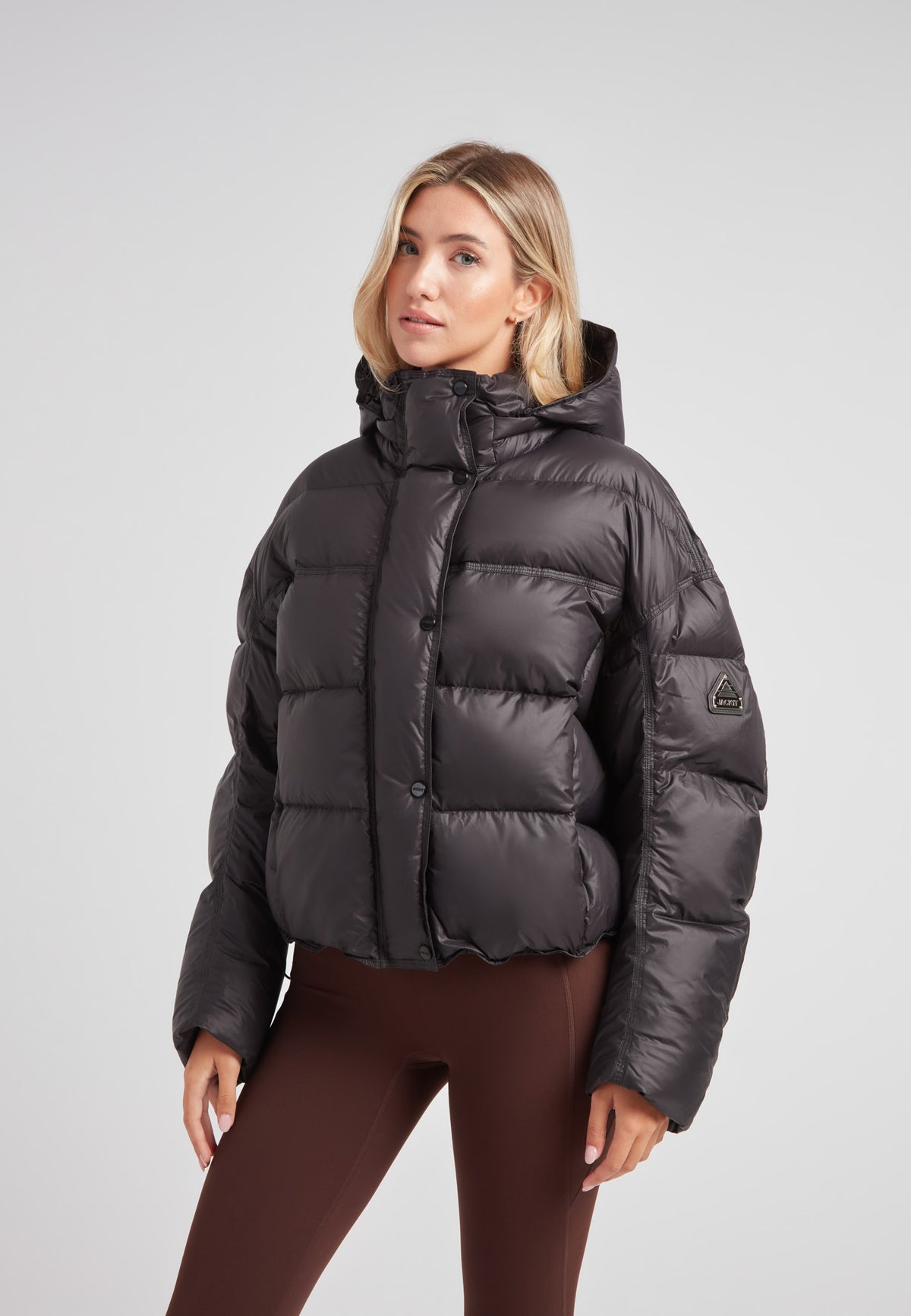 Cropped puffer in black with adjustable coverage worn by a model, showcasing oversized streetwear style.