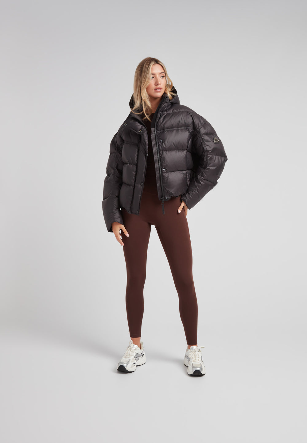 Model wearing Cloud Boss cropped puffer in black with adjustable coverage and leggings for a trendy winter look.