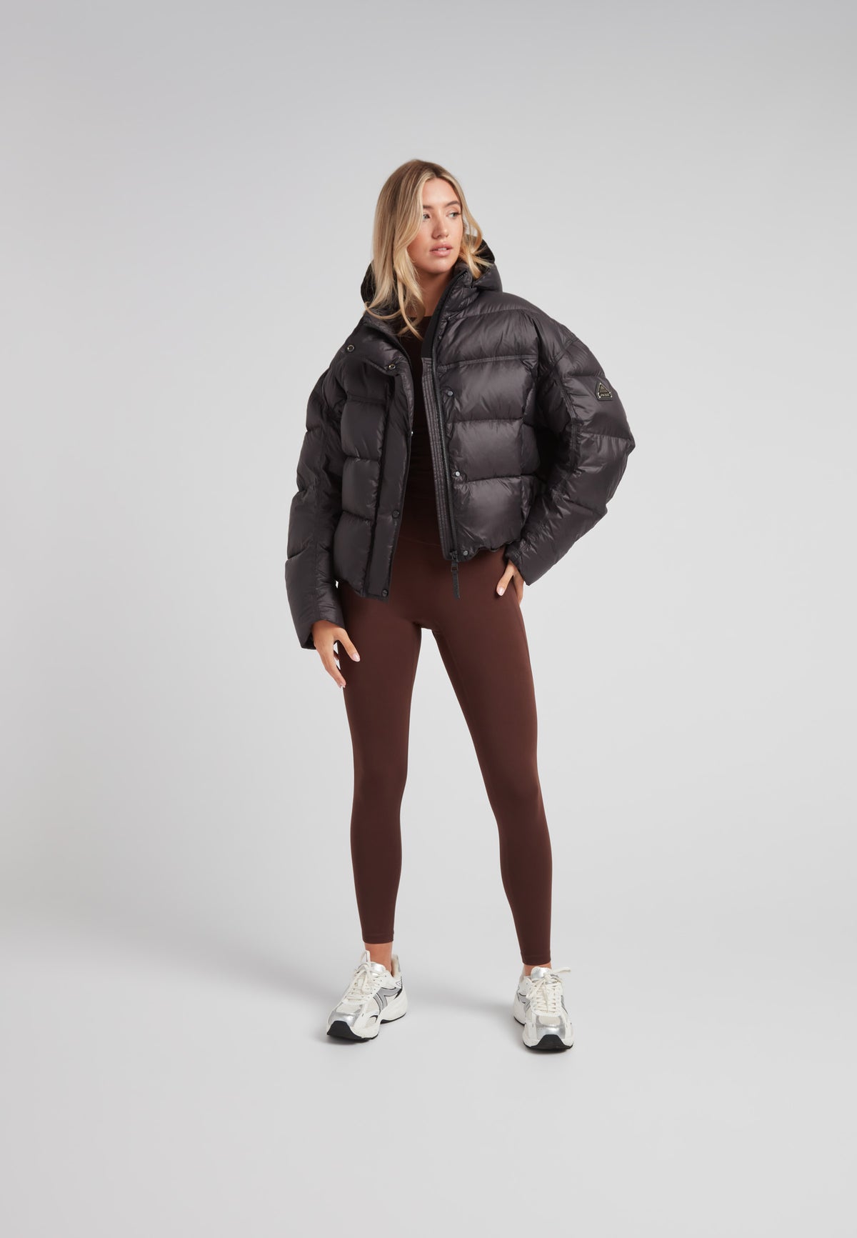 Model wearing Cloud Boss cropped puffer in black with adjustable coverage and leggings for a trendy winter look.
