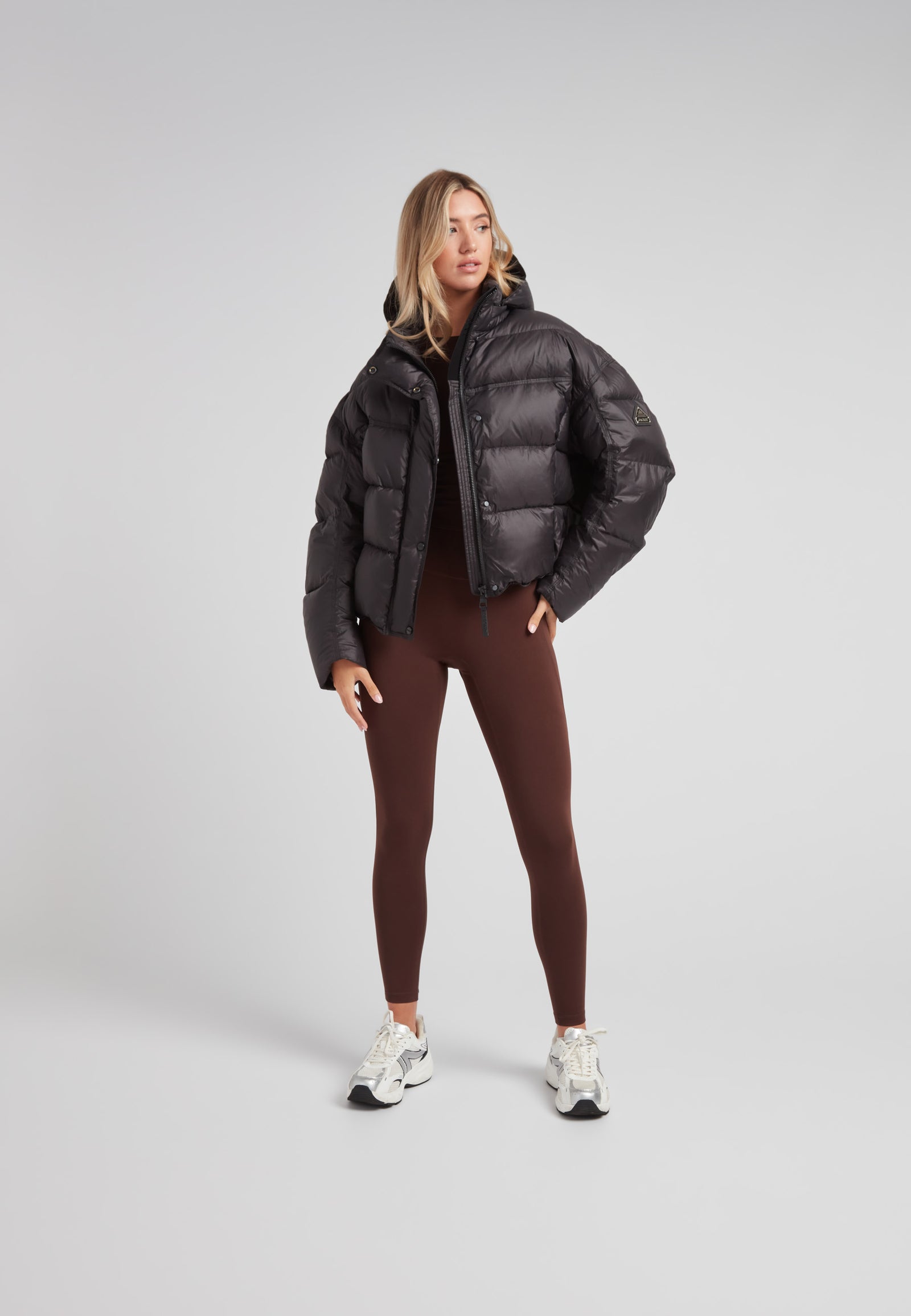 Model wearing Cloud Boss cropped puffer in black with adjustable coverage and leggings for a trendy winter look.
