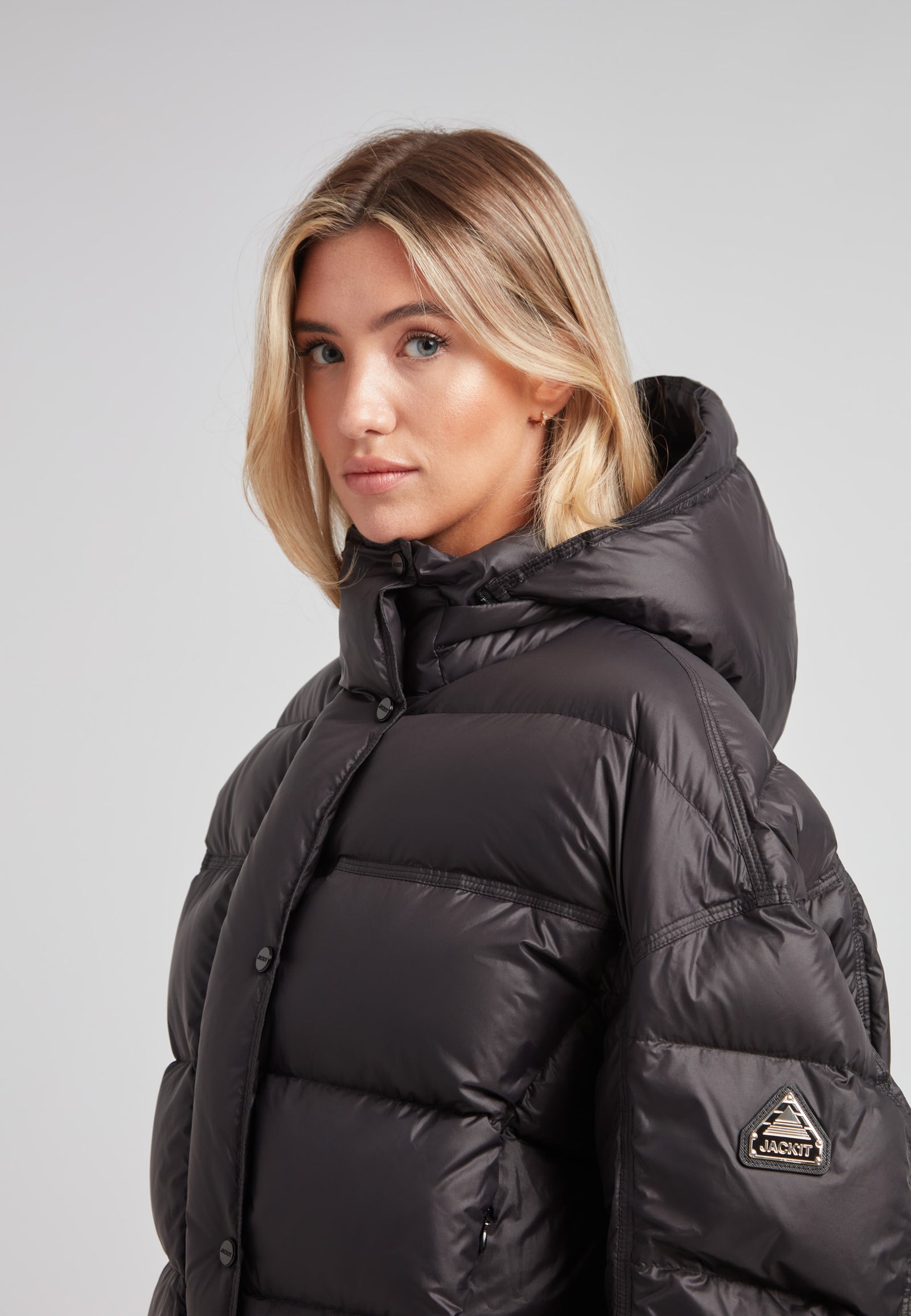 Cropped puffer in black with adjustable coverage, featuring a stylish design and removable hood for winter wear.