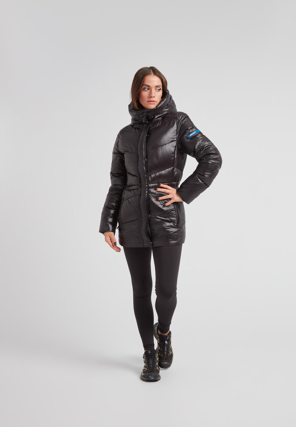 Black thigh-length womens slick coat worn by model, featuring a mid-length silhouette and water-repellent finish.