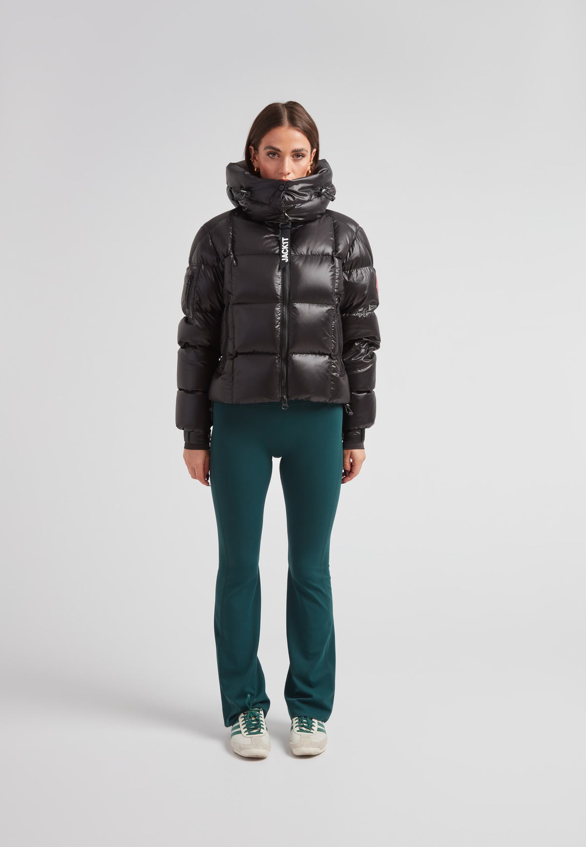 Woman wearing the EZ Boxed Crop Down Puffer Jacket Lux Black with green pants, showcasing winter style and warmth.