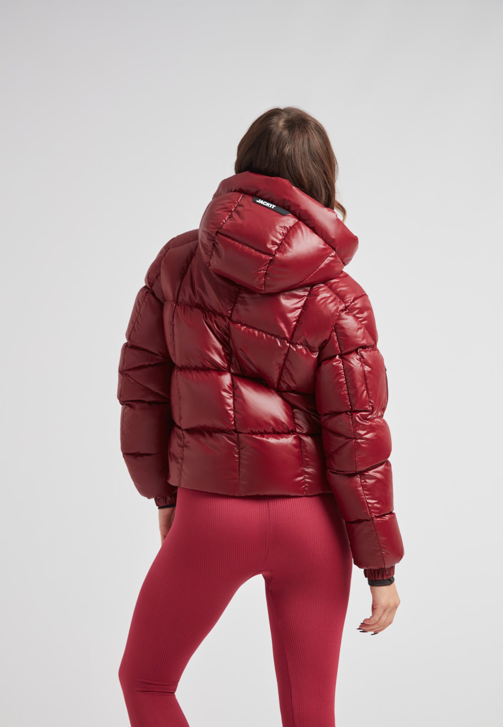 Back view of a woman wearing the EZ Boxed Crop Down Puffer Jacket Lux Cranberry with matching leggings.