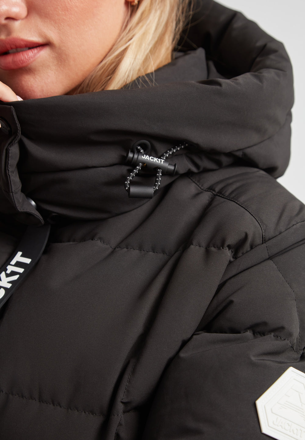 Close-up of a woman wearing the EZ Boxed Racer Down Puffer Jacket Matt Black with details of the hood and texture.