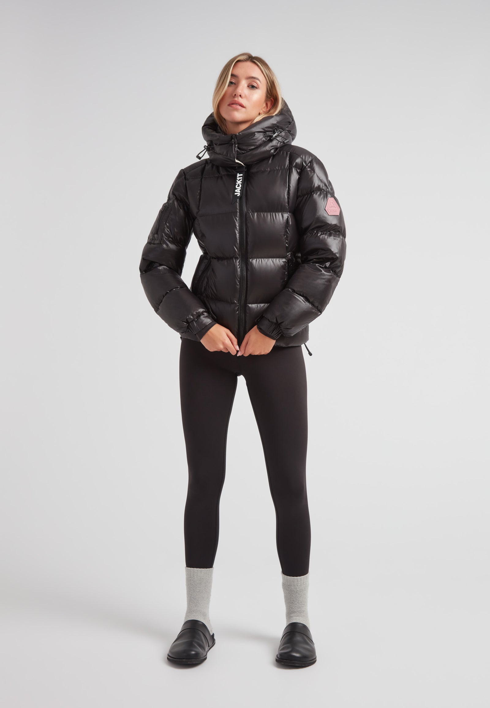 Model wearing EZ Boxed Racer Down Puffer Jacket Lux Black with sleek design and hood, paired with black leggings.