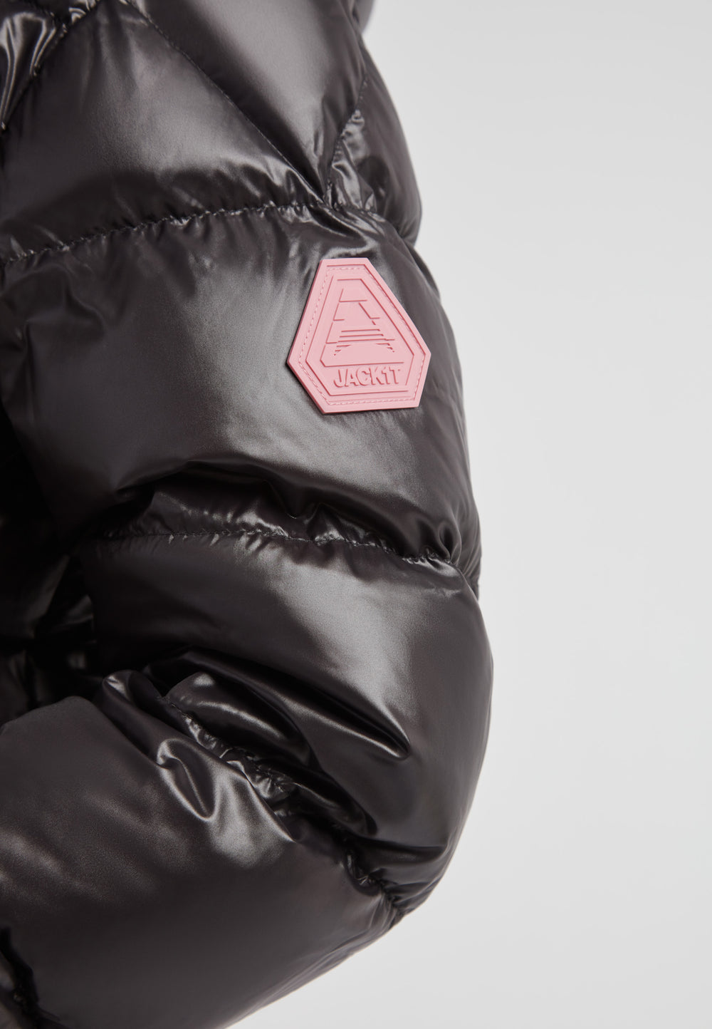 EZ Boxed Racer Down Puffer Jacket Lux Black close-up of brand badge detail.