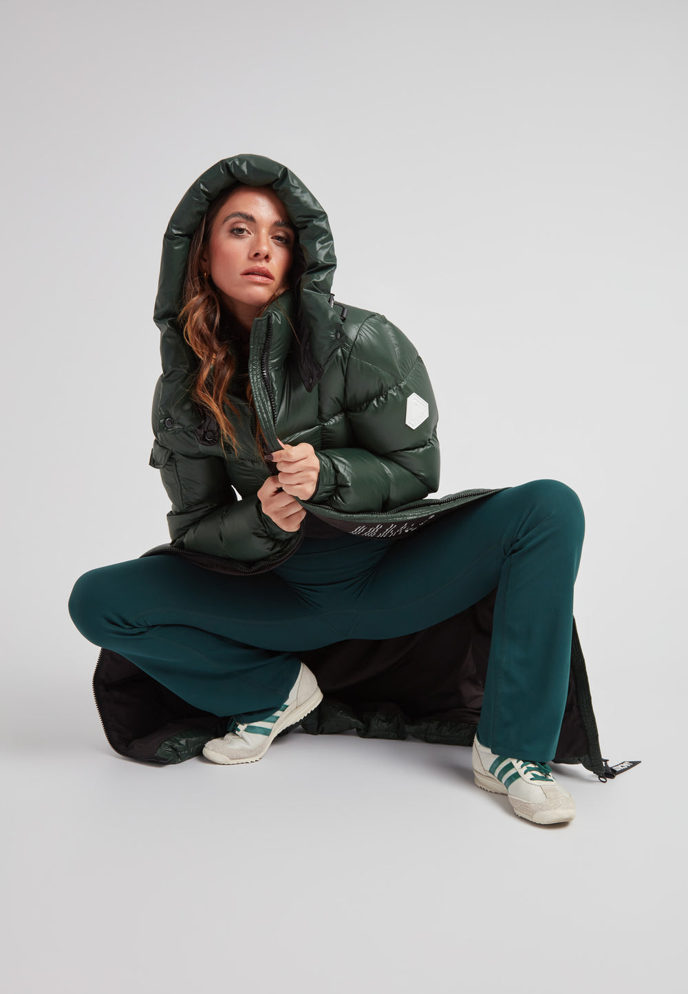 Woman wearing EZ Boxed Ultra Long Down Puffer Coat Lux Emerald, posing in a stylish athletic outfit.
