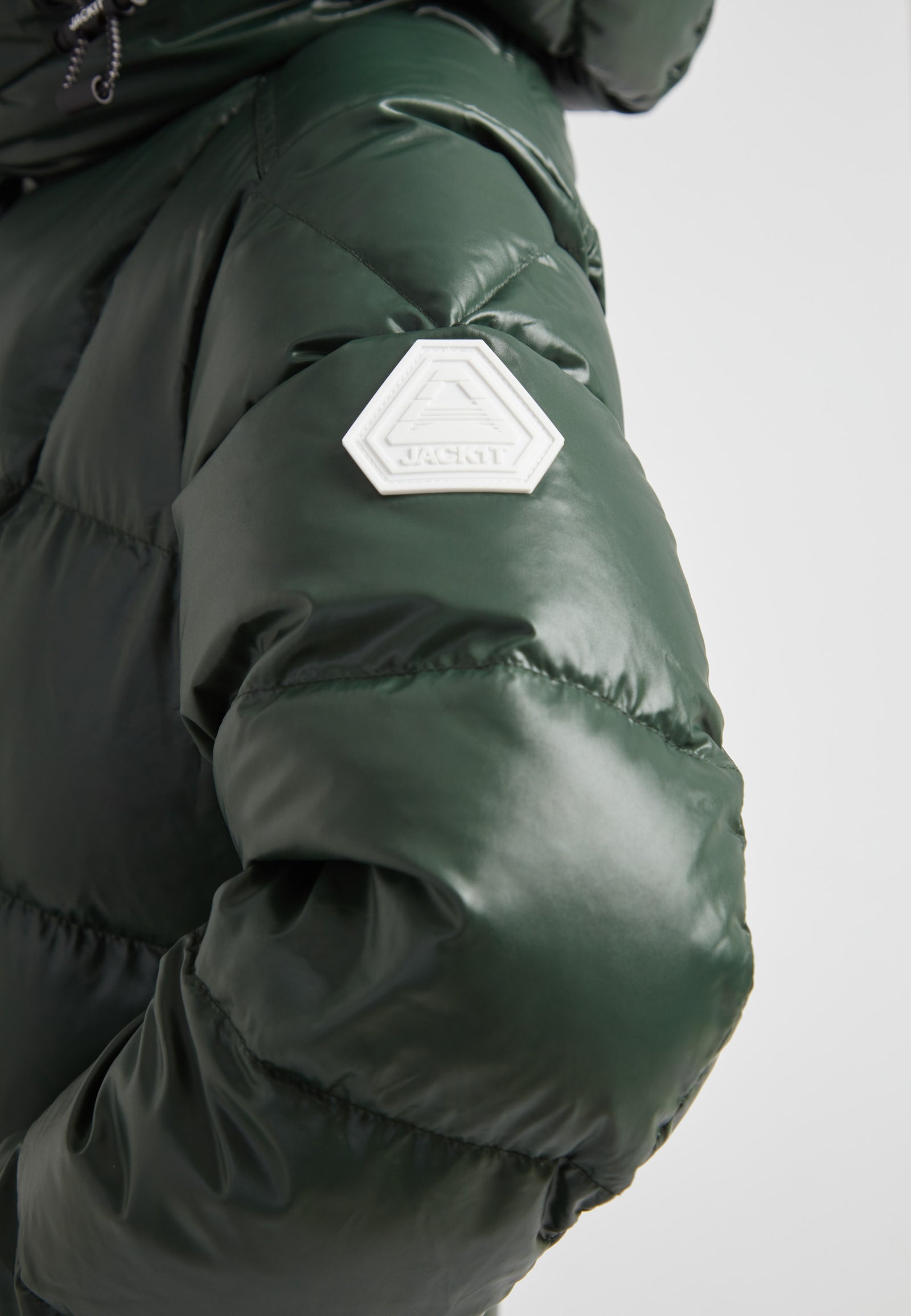 Close-up of the EZ Boxed Ultra Long Down Puffer Coat Lux Emerald, highlighting the glossy green fabric and logo patch.