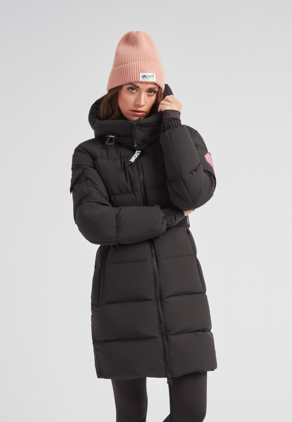 Model wearing the EZ Belted Down Puffer Coat Matt Black with a pink beanie, showcasing its stylish design.