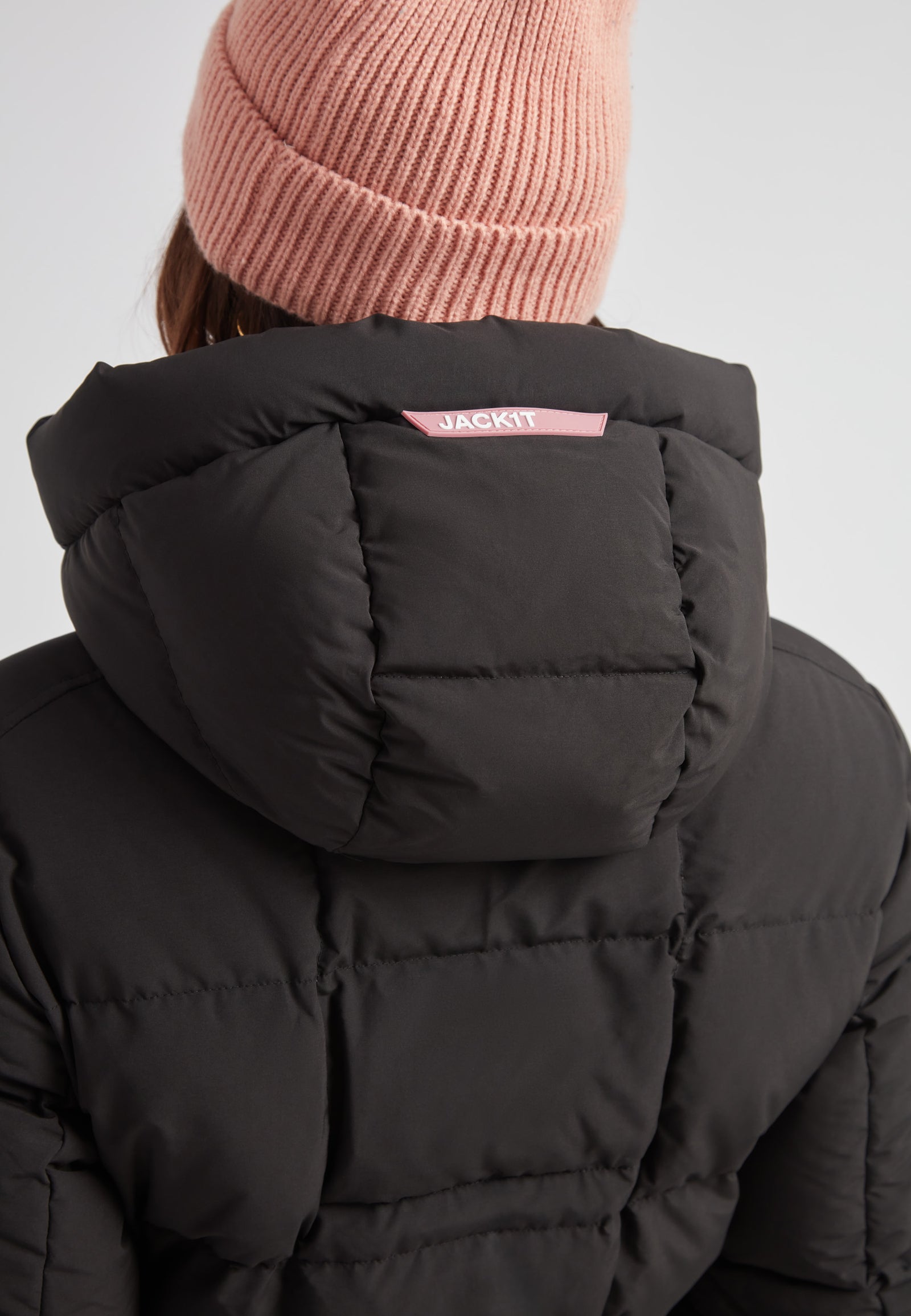 Woman wearing the EZ Belted Down Puffer Coat Matt Black with a pink beanie.