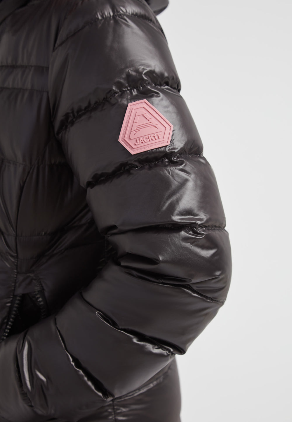 R4D Tramline Extra Long Down Coat Lux Black featuring a shiny black shell and a pink badge on the sleeve.