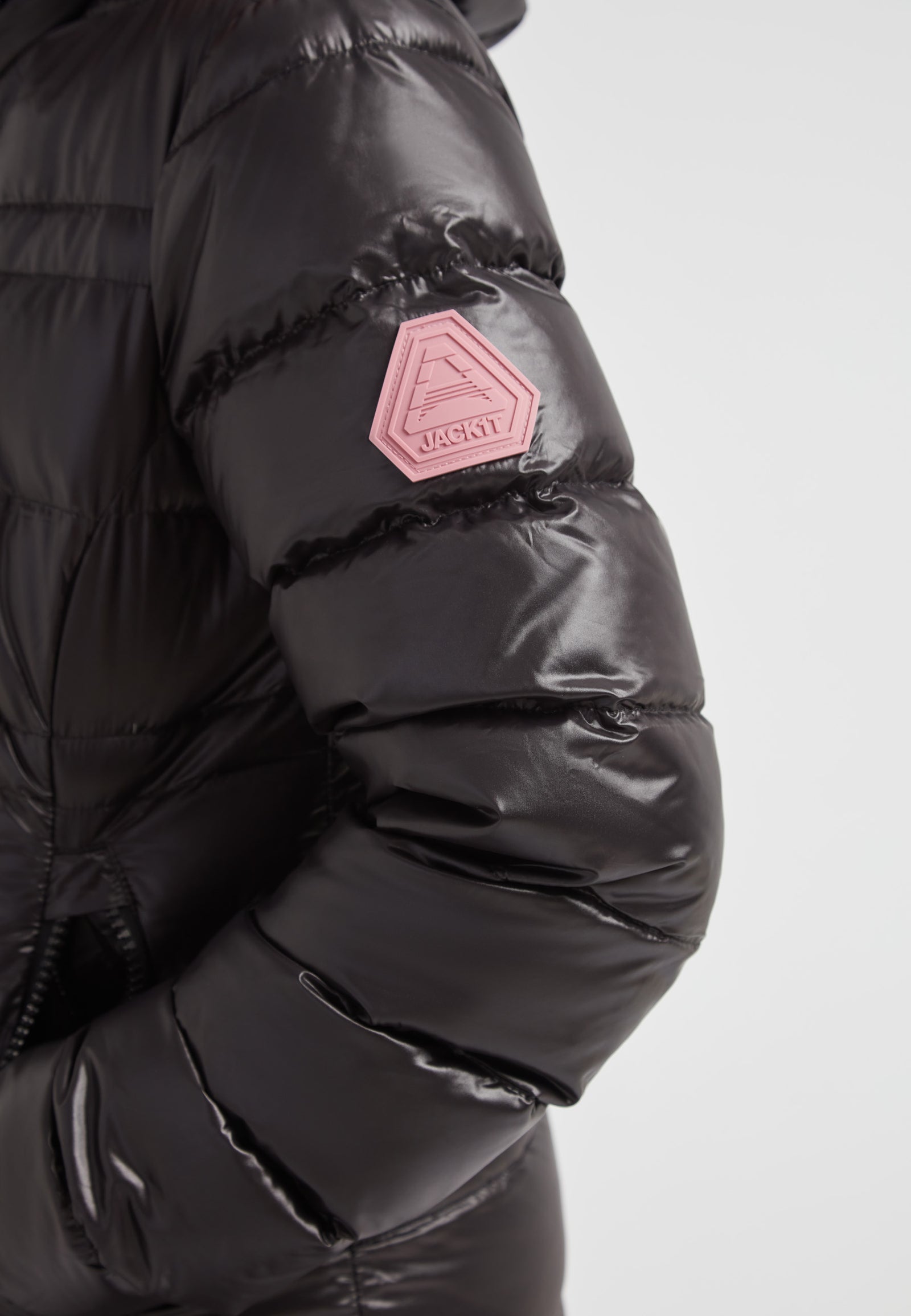 R4D Tramline Extra Long Down Coat Lux Black featuring a shiny black shell and a pink badge on the sleeve.