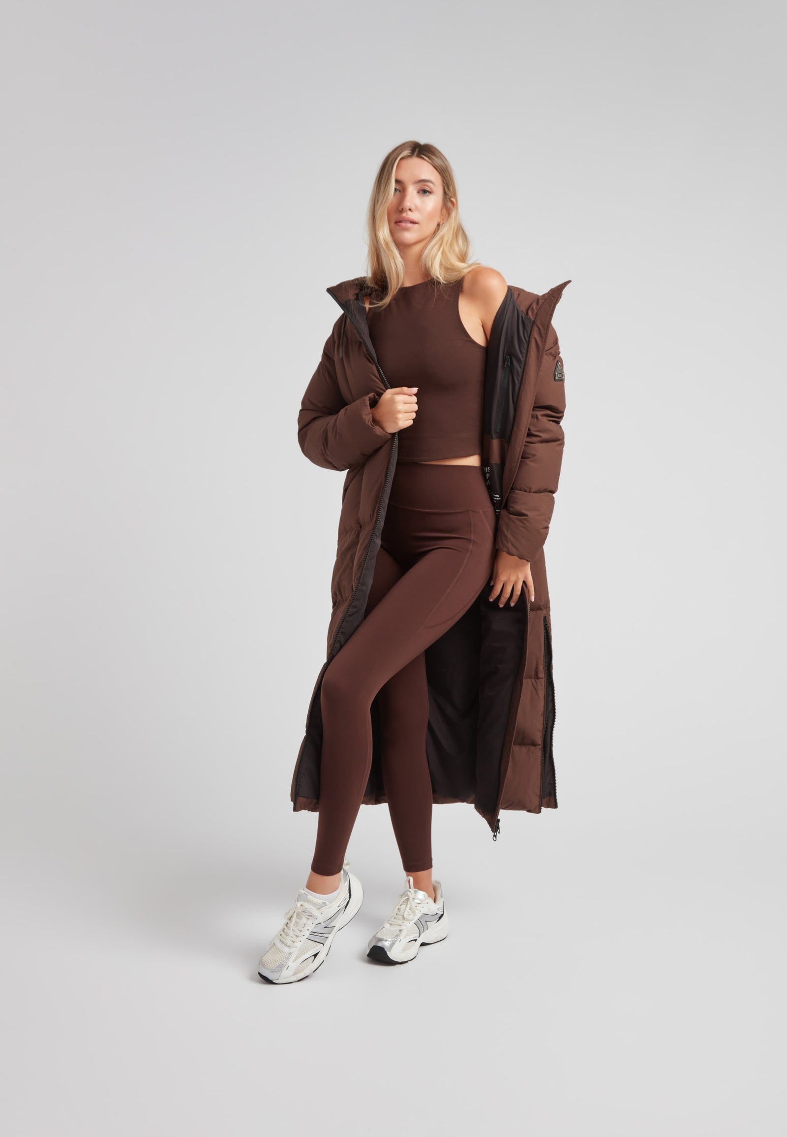 Model wearing Black Star Extra Long Down Coat Matt Mid Brown, showcasing its extended design and modern style.
