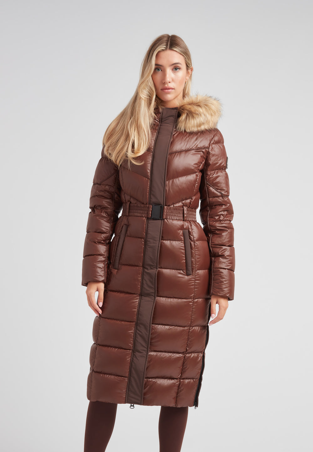 Women's puffer coat with fur hood in brown, featuring a belted waist and a sleek, insulated design.