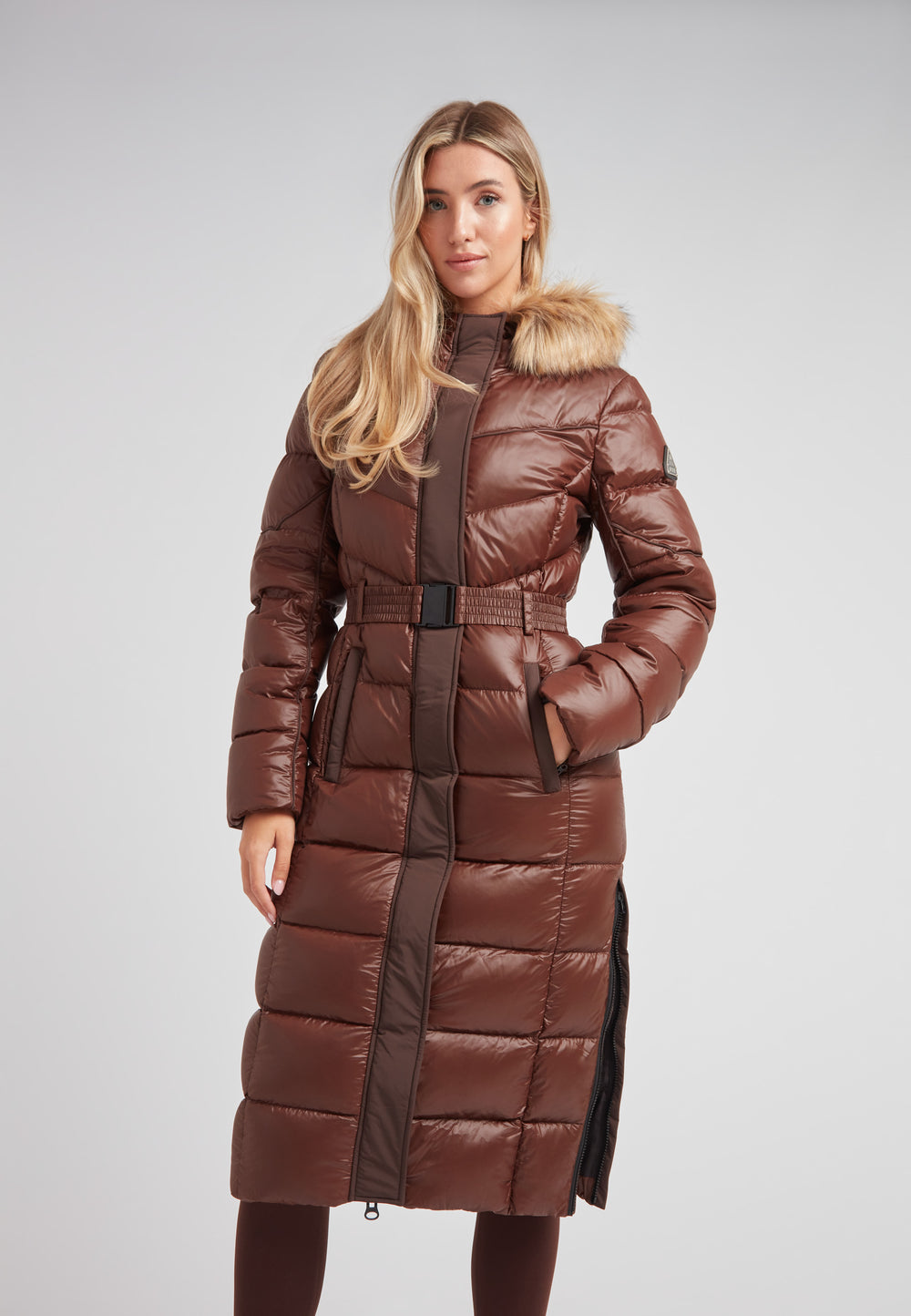 Women's puffer coat with fur hood in brown, featuring a belted waist and plush hood for warmth and style.
