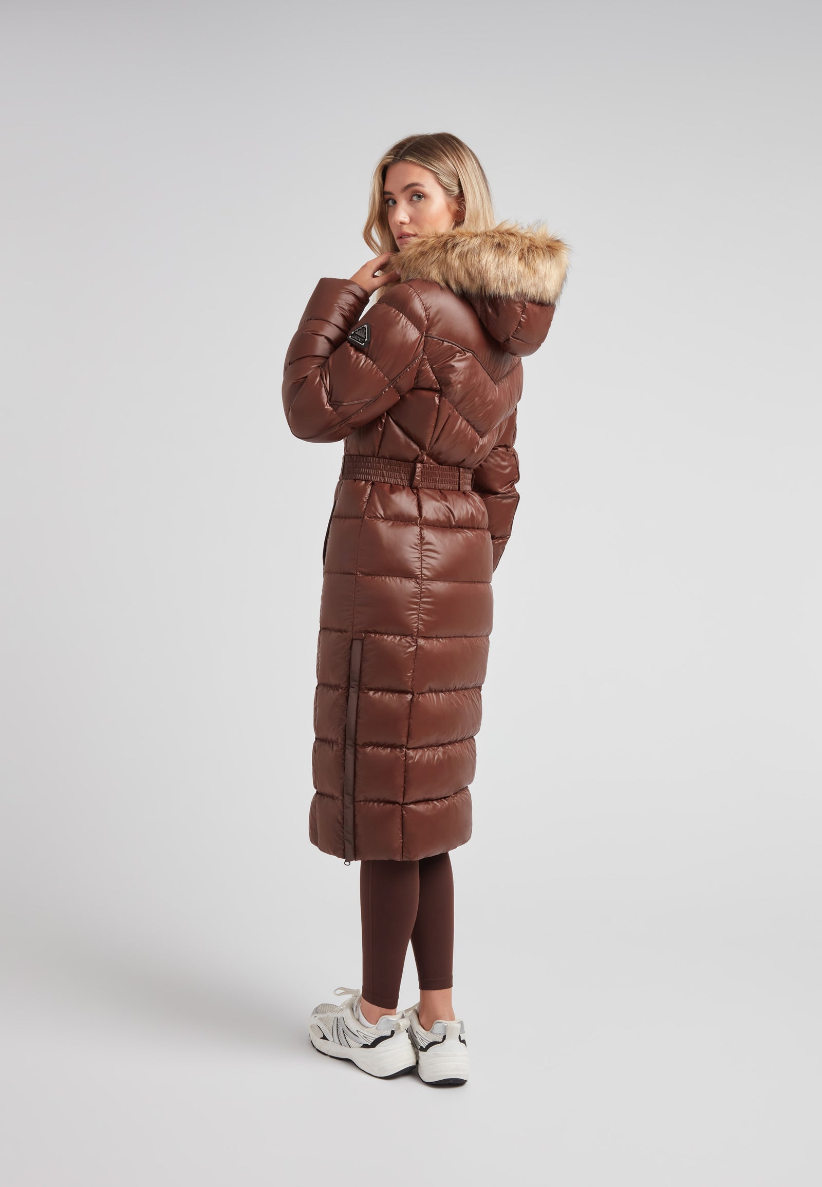 Women's puffer coat with fur hood in brown, featuring a belted design and stylish mid-brown color.