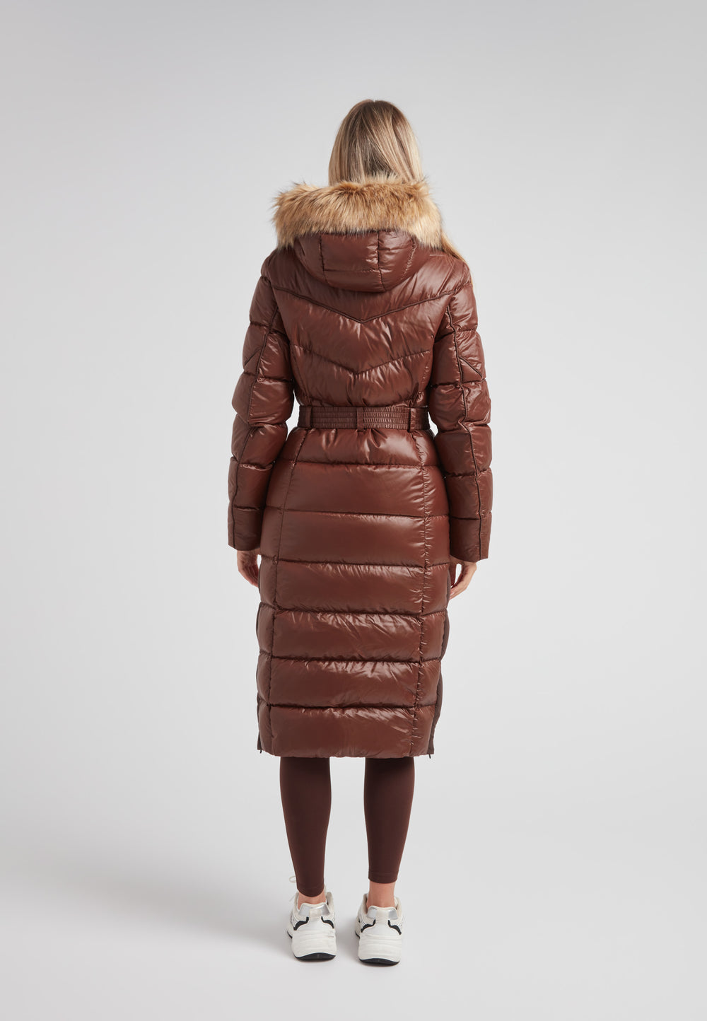 Women's puffer coat with fur hood in brown, featuring a belted design and extra long length for stylish warmth.