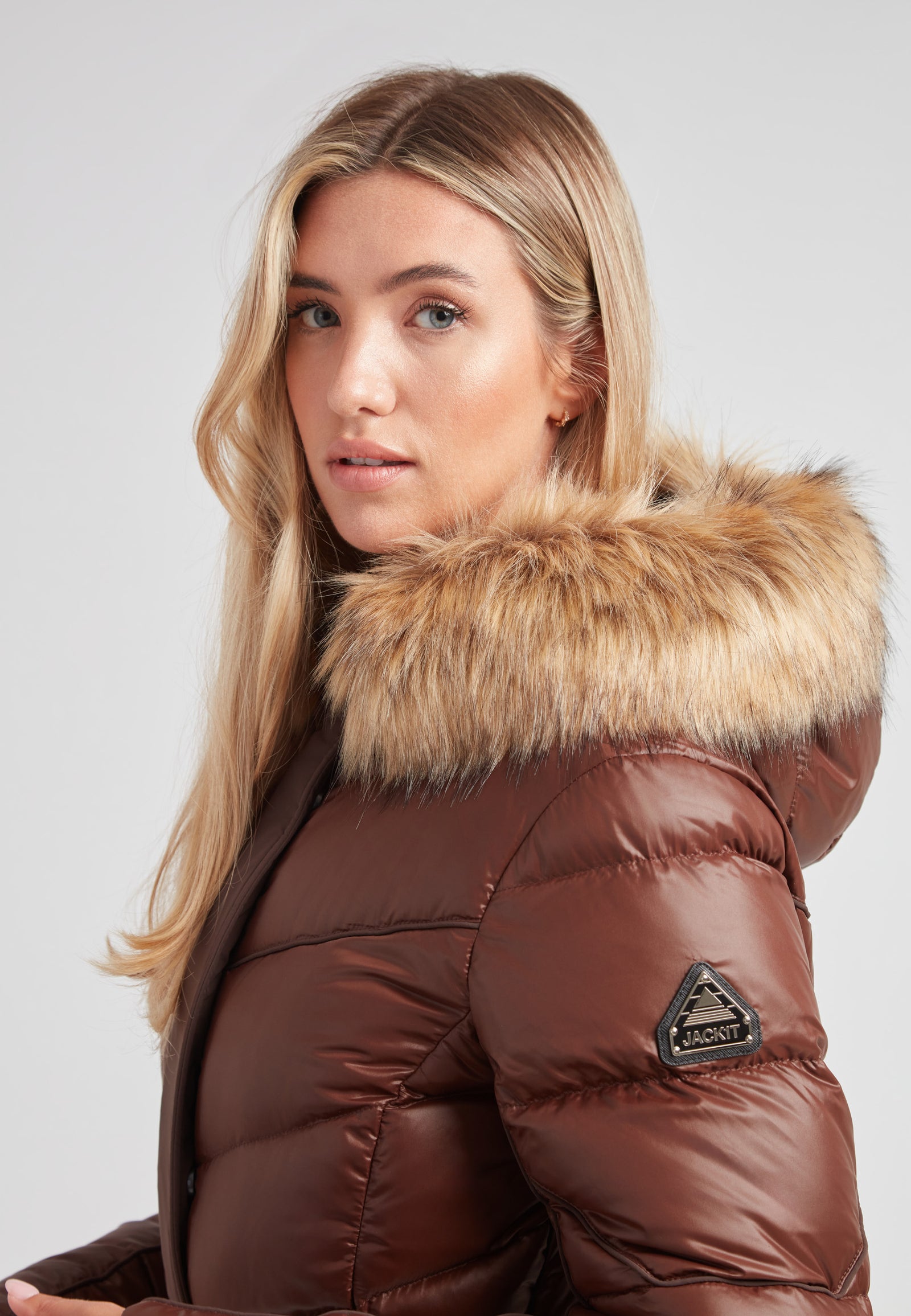 Women's puffer coat with fur hood in brown, featuring a stylish design and luxurious faux fur trim.