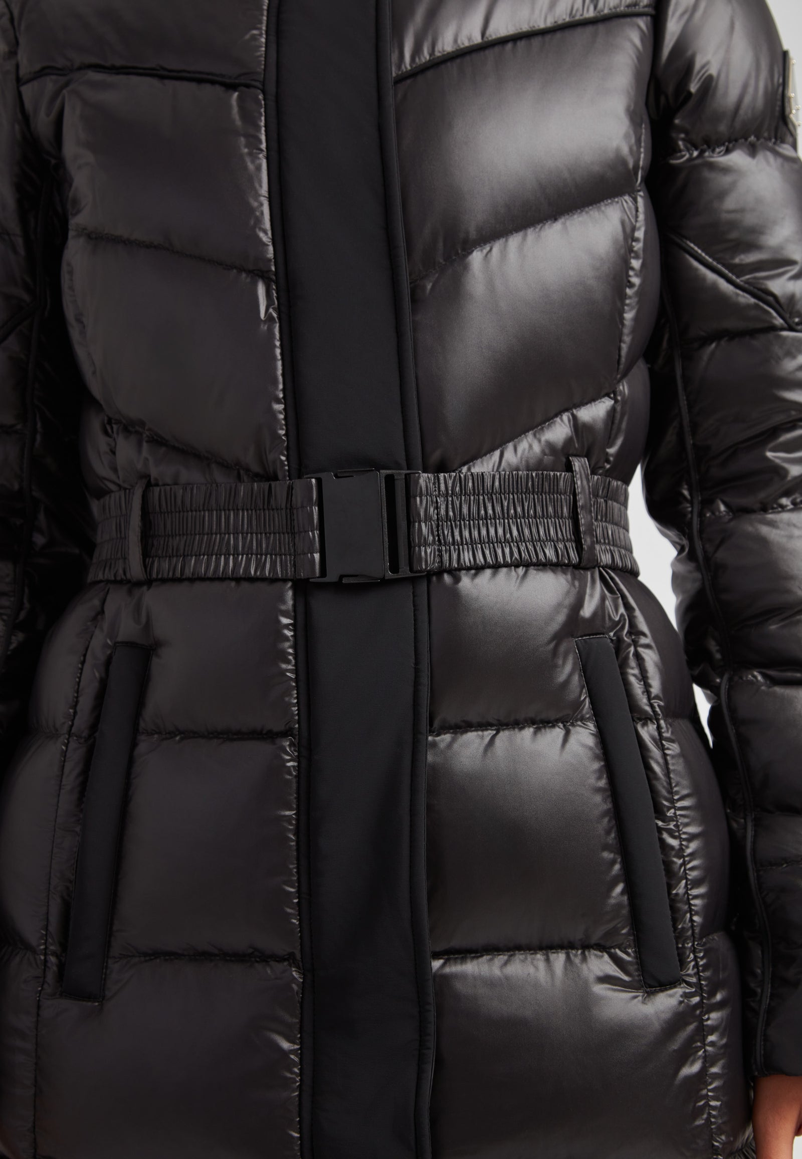 Women's puffer coat with fur hood in black featuring a belted design and quilted texture.
