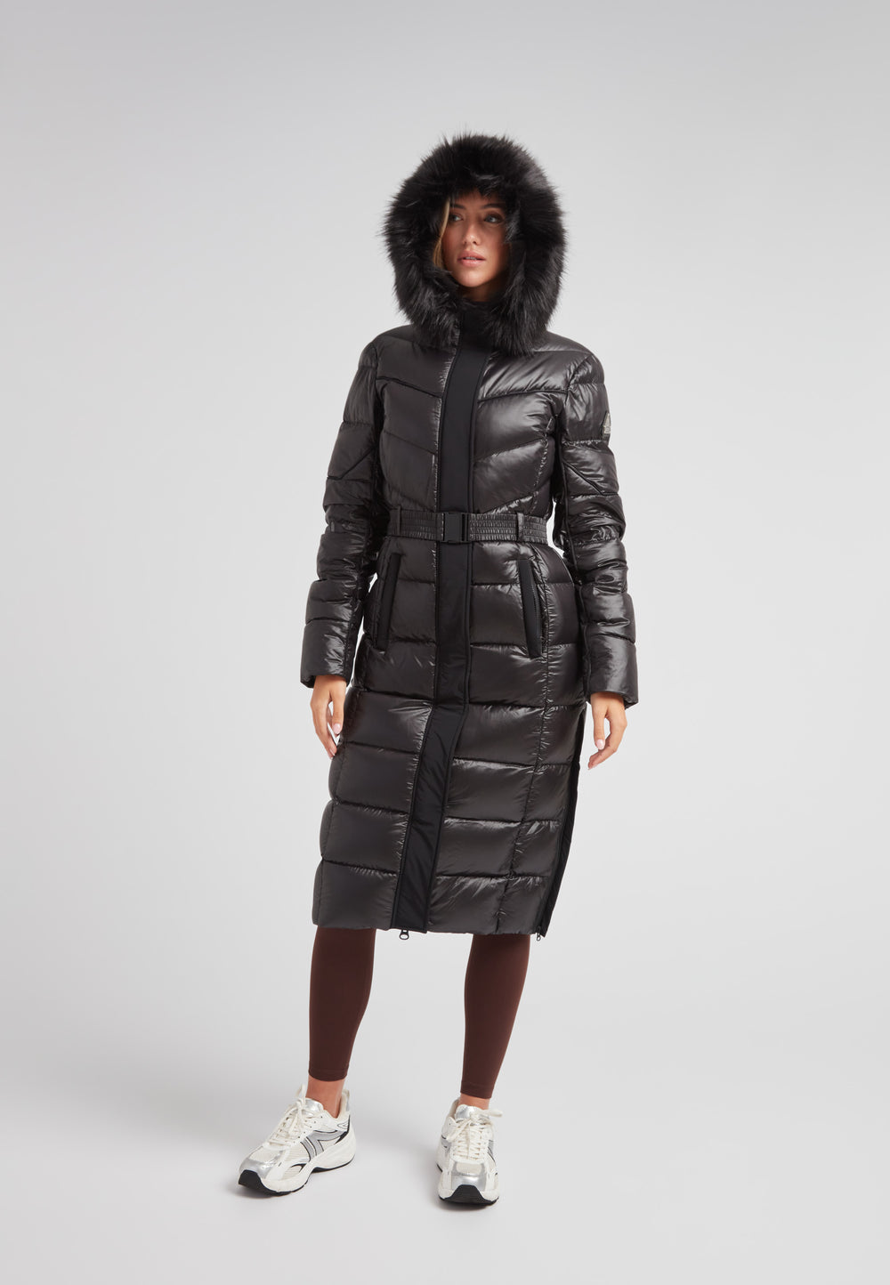 Women's puffer coat with fur hood in black featuring a belted design and full-length silhouette.