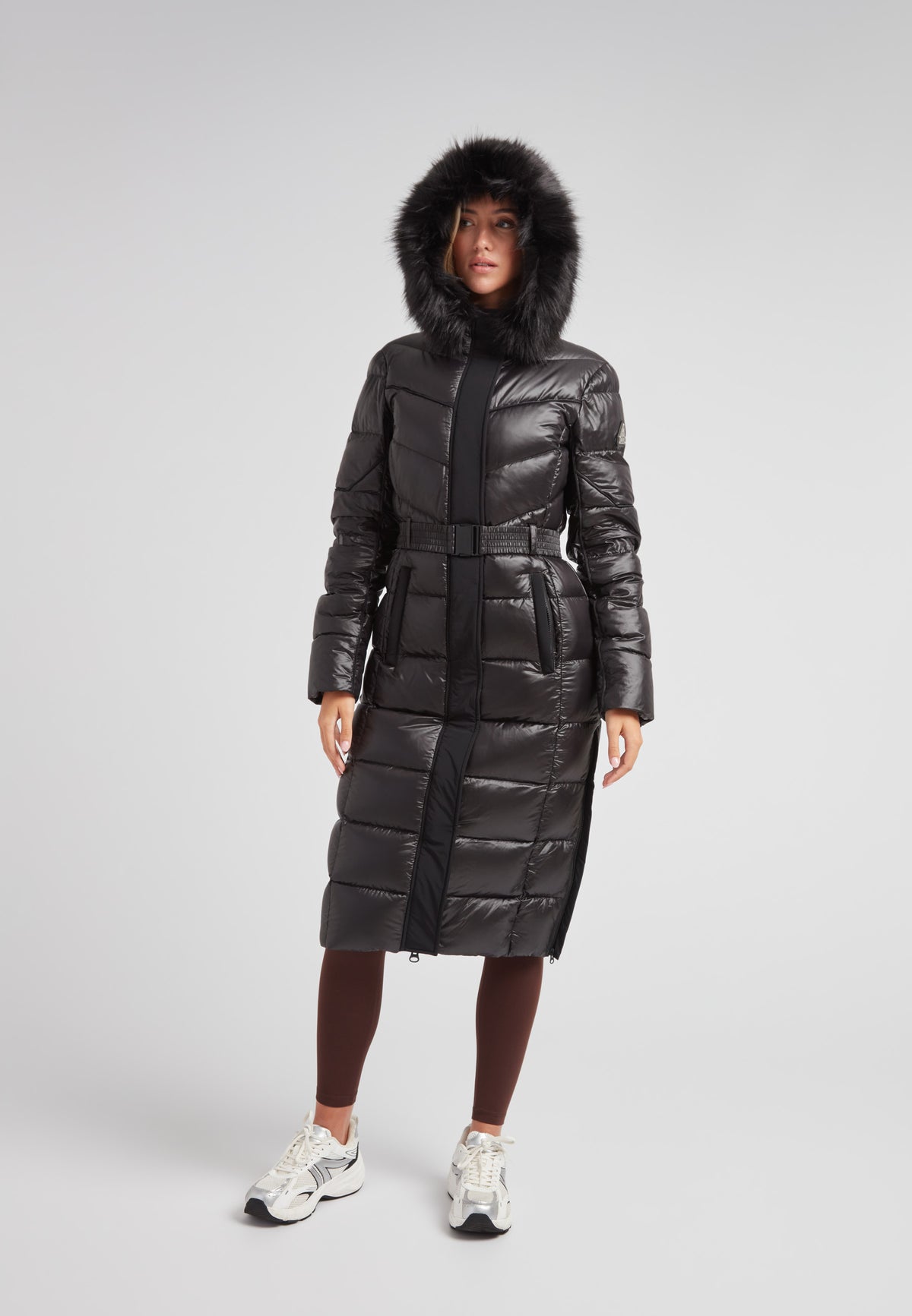 Women's puffer coat with fur hood in black featuring a belted design and full-length silhouette.