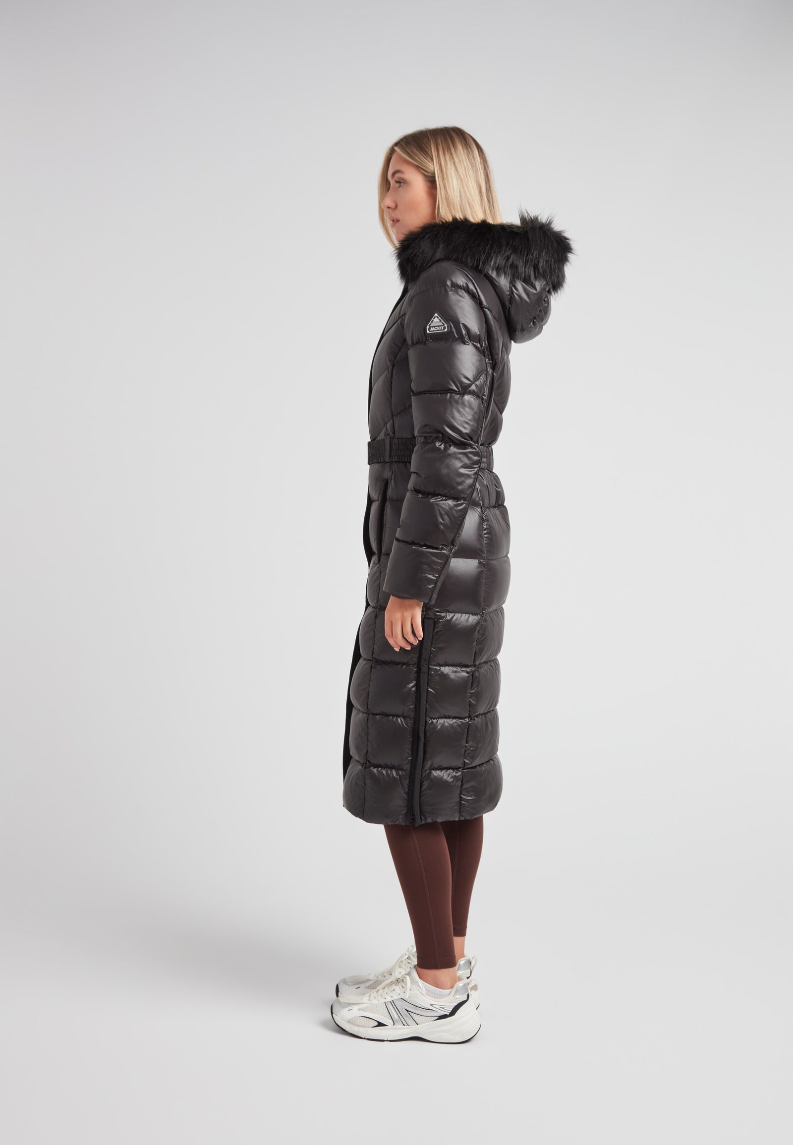 Women's puffer coat with fur hood in black featuring a stylish belted design and full-length silhouette.