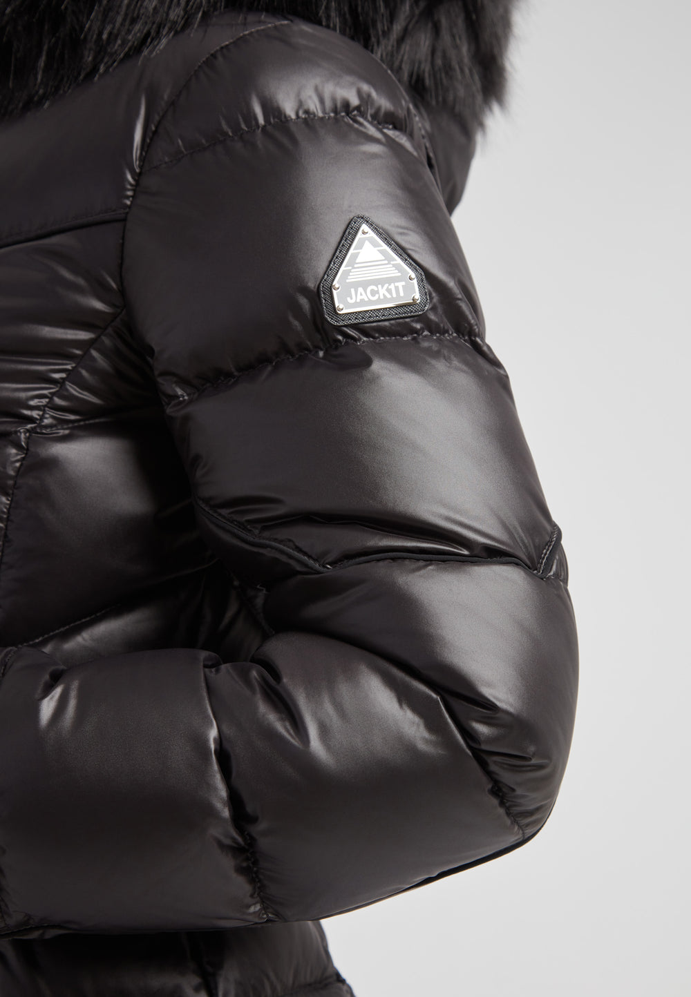 Women's puffer coat with fur hood in black showcasing the stylish sleeve and logo detail.