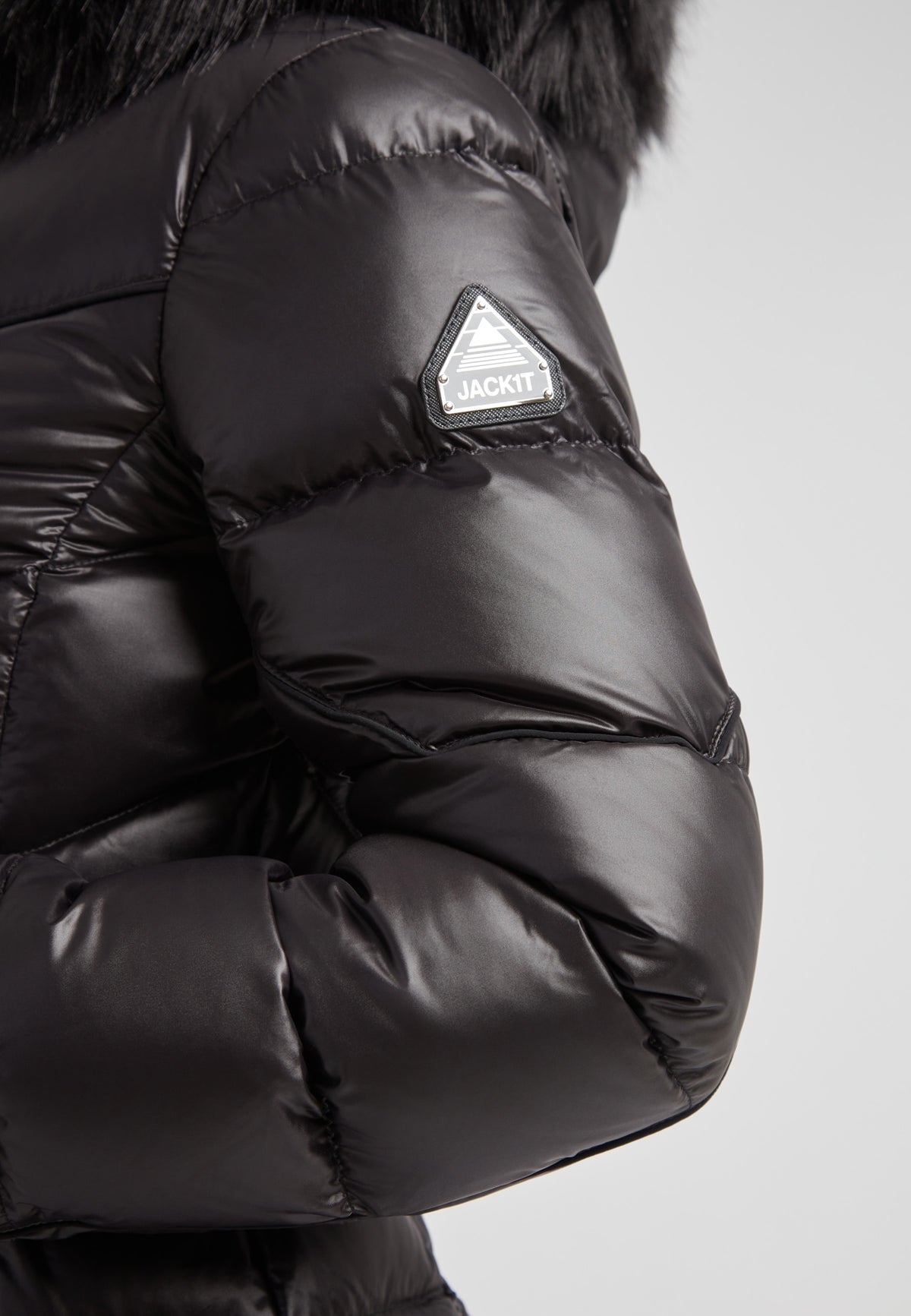 Women's puffer coat with fur hood in black showcasing the stylish sleeve and logo detail.