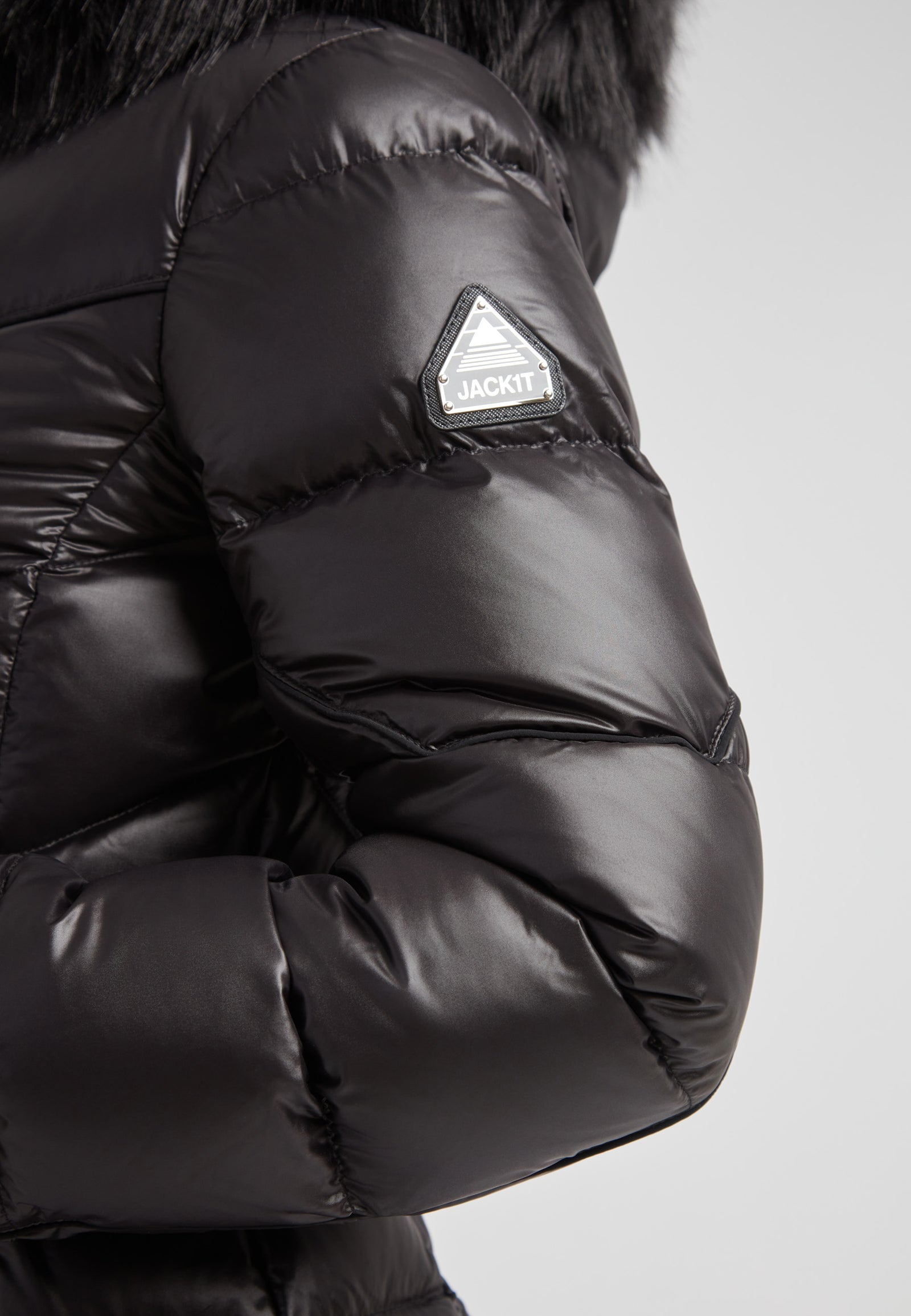 Women's puffer coat with fur hood in black showcasing the stylish sleeve and logo detail.