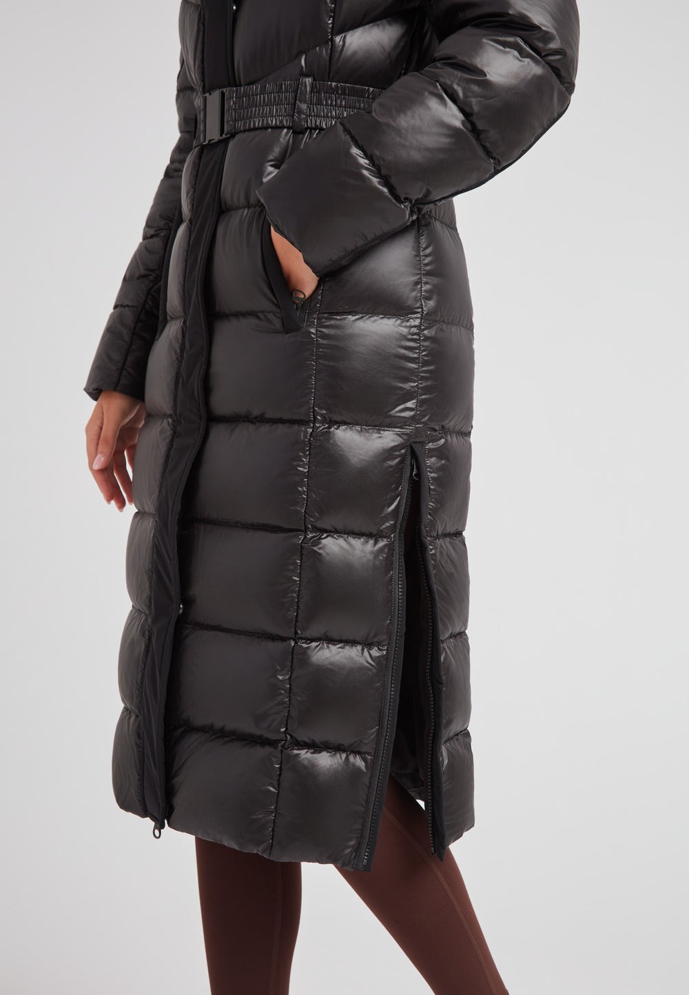 Women's puffer coat with fur hood in black featuring a belted design and side zip pockets.