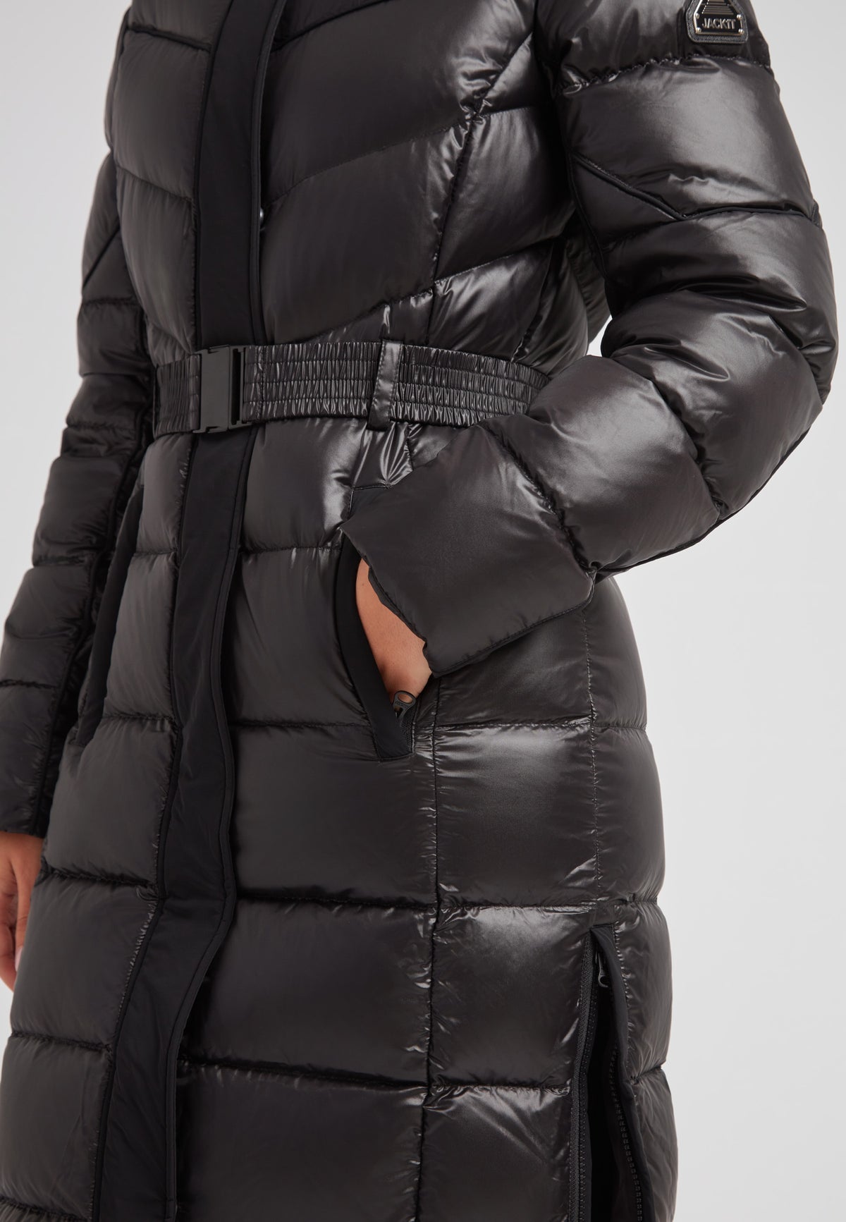 Women's puffer coat with fur hood in black featuring a belted waist and side pockets.