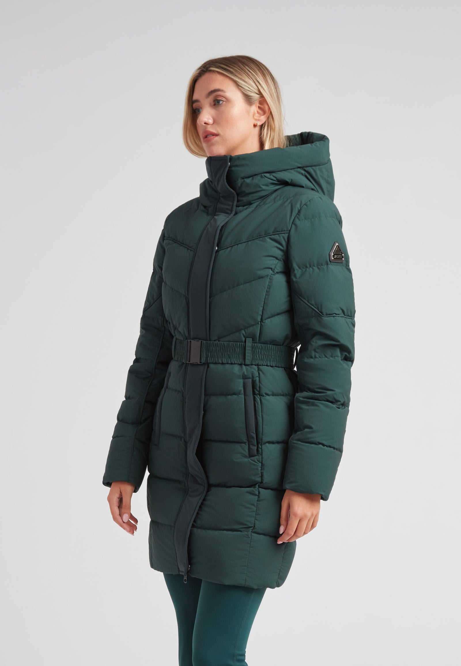 Diamond Belted Down Coat Matt Emerald worn by a woman, showcasing its sophisticated design and winter functionality.