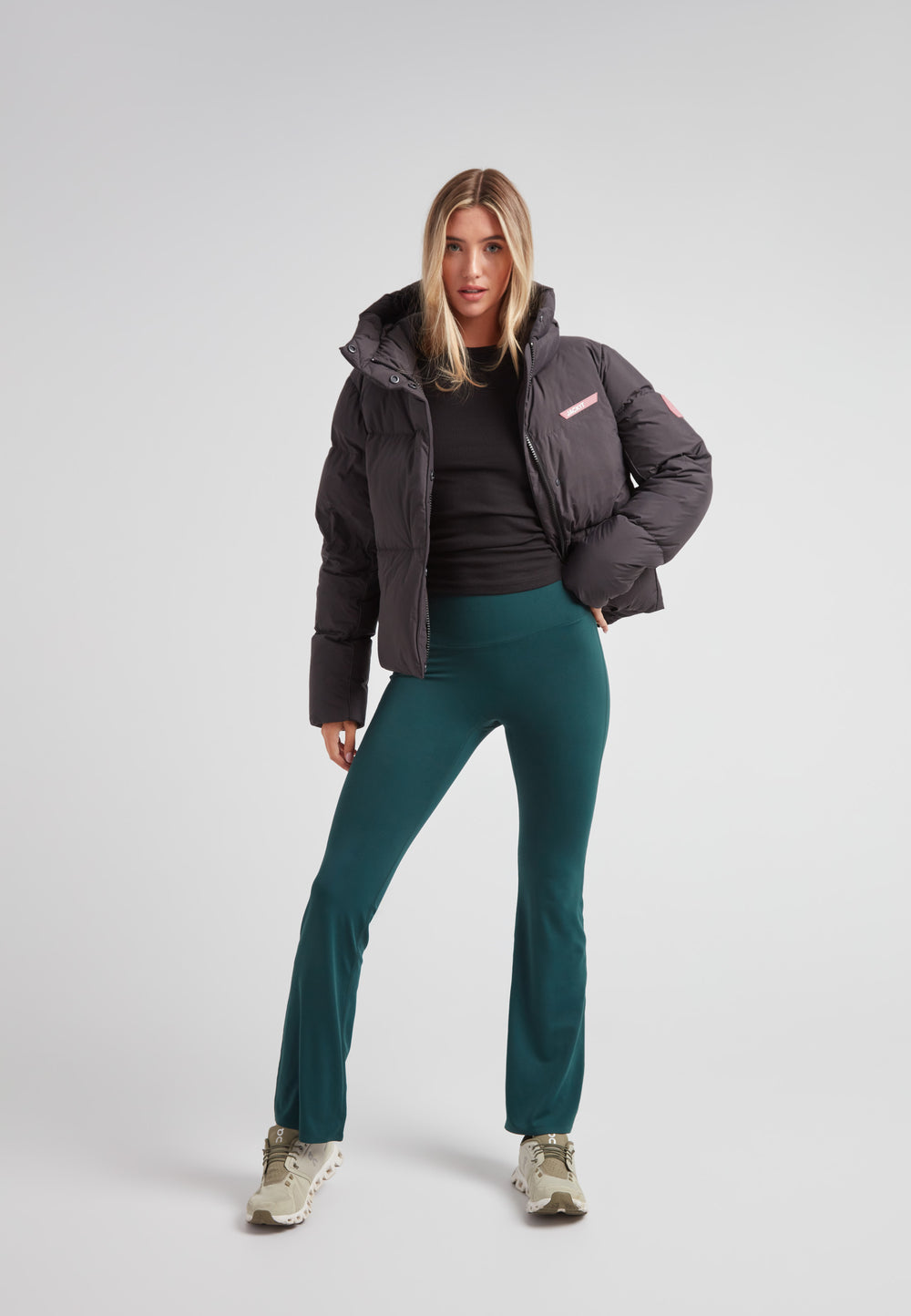 Woman wearing the Star Shower Down Puffer Jacket Black with teal pants and casual shoes.