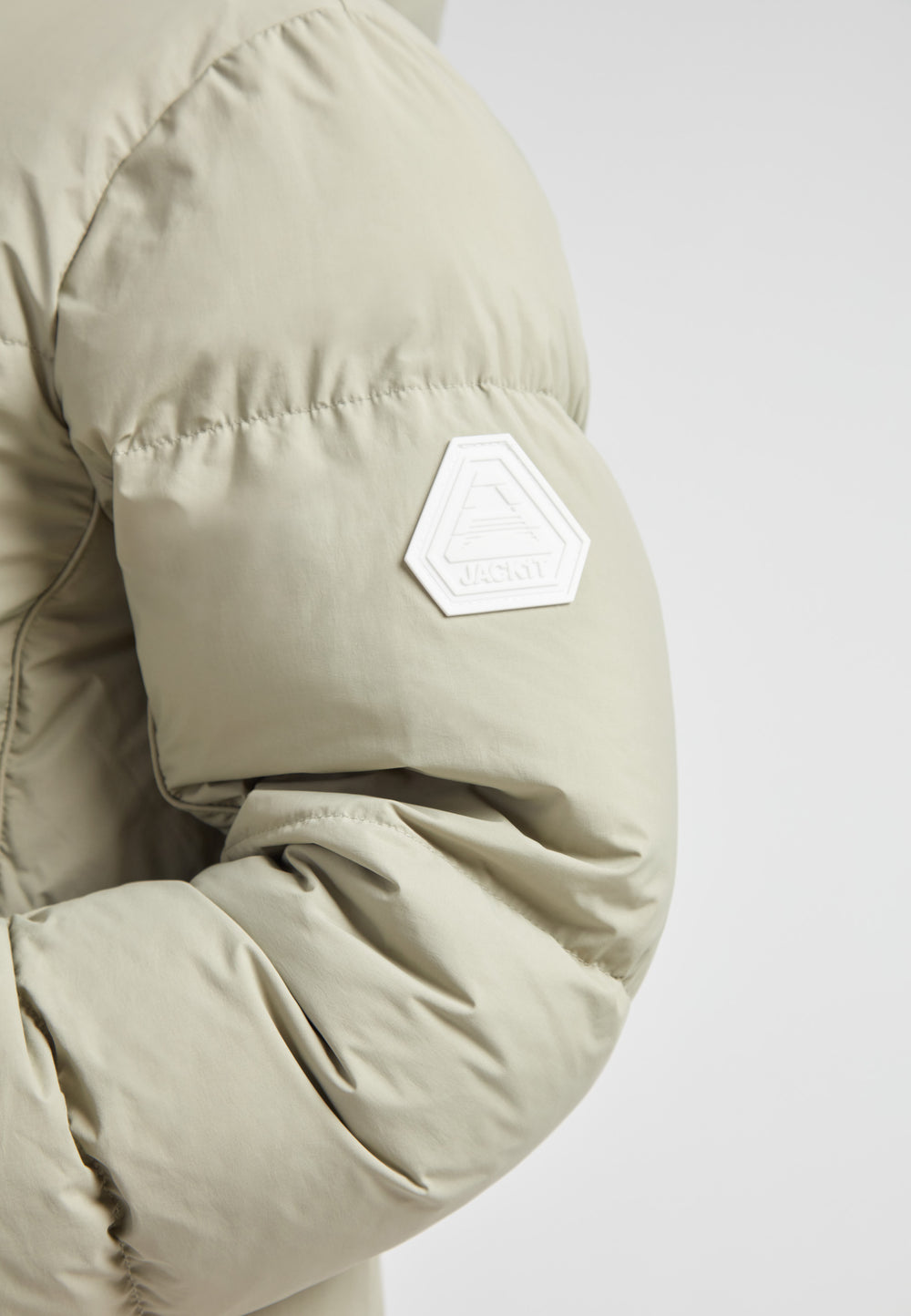Close-up of the sleeve of the Star Shower Down Puffer Jacket Sage showcasing its stylish design and logo.