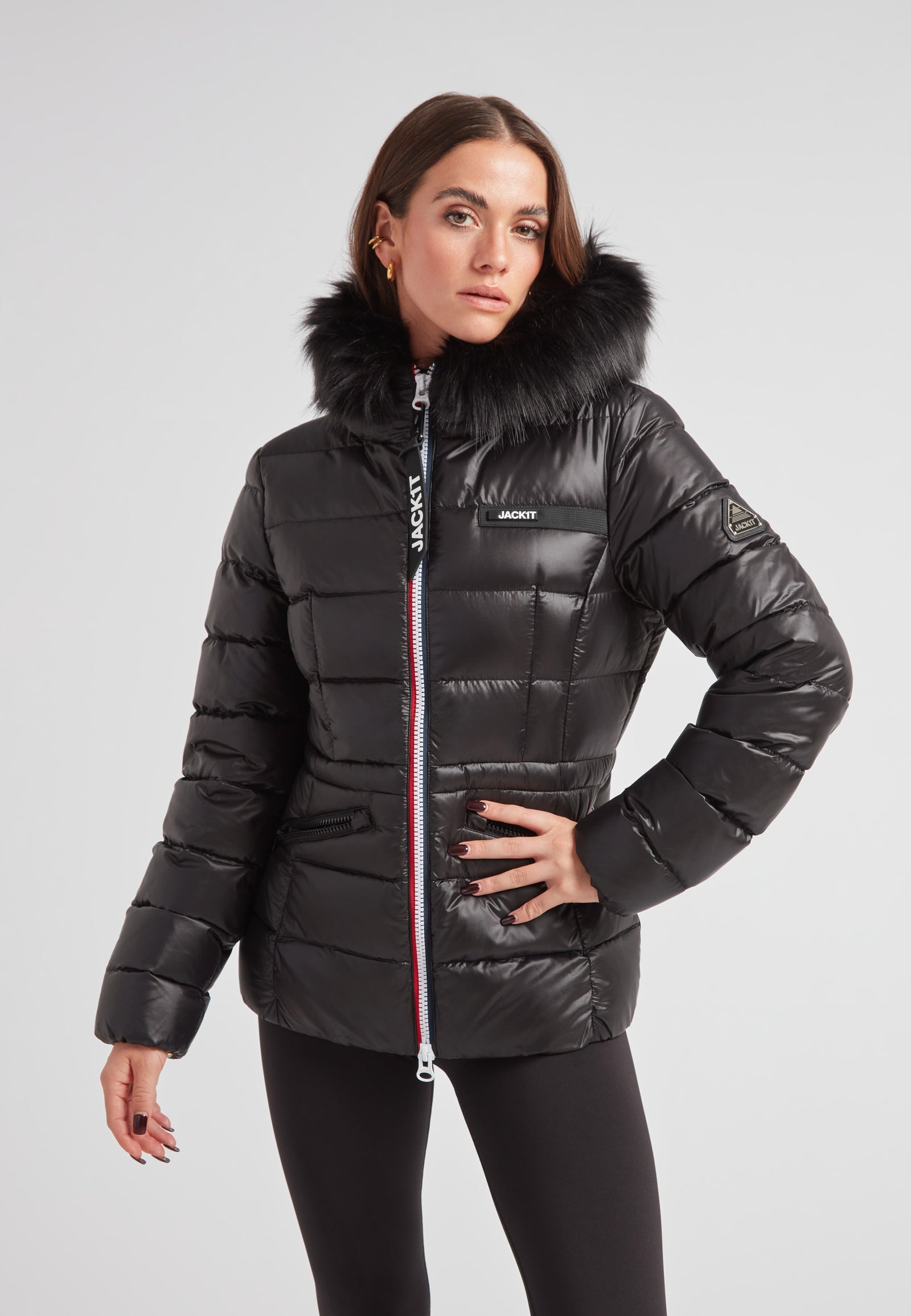 Black racer puffer jacket with fur hood worn by a model, showcasing alpine style and warmth.